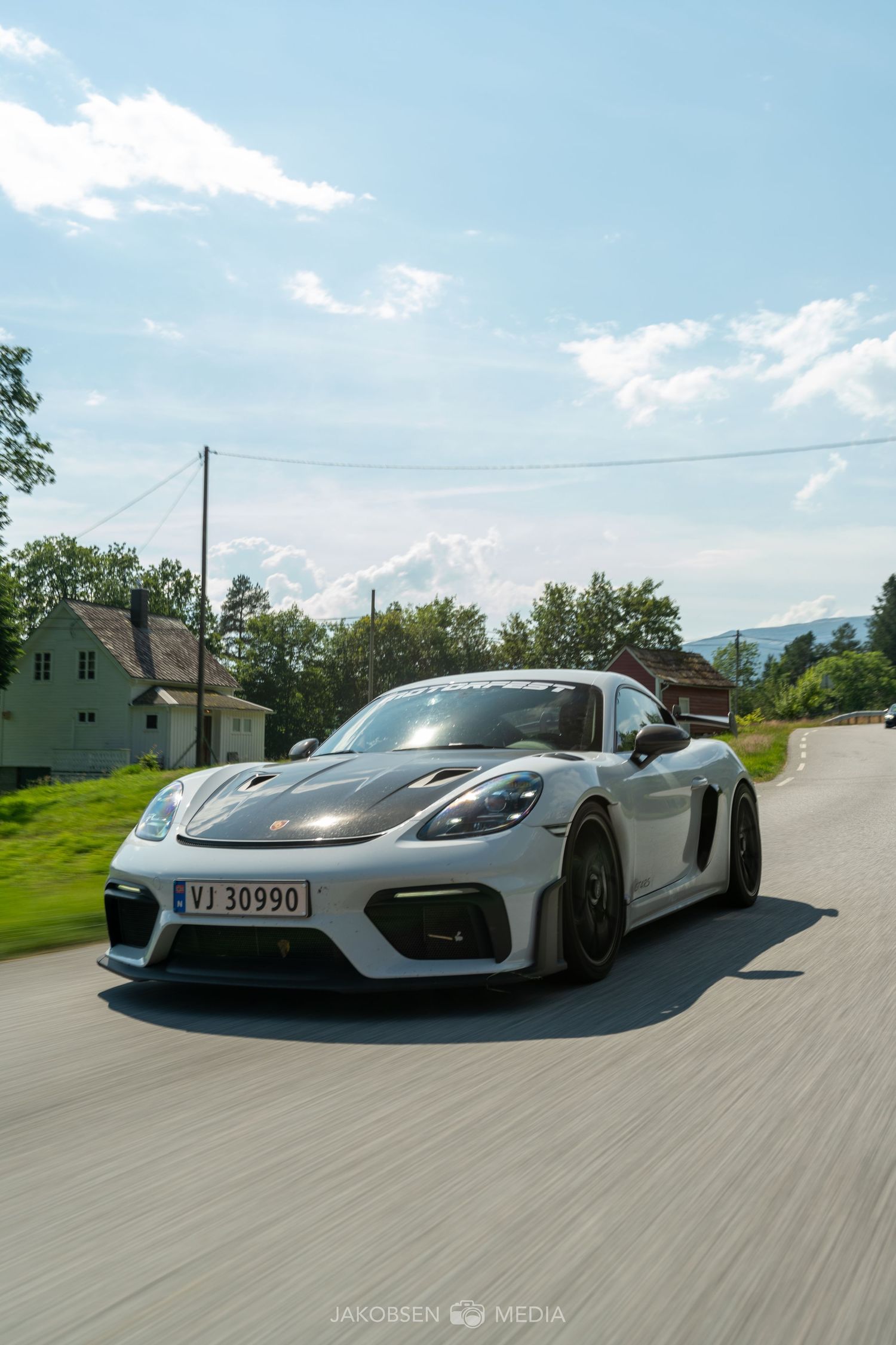 A white Porsche 911 GT3 RS sports car captured on a scenic mountain road from multiple dynamic angles.