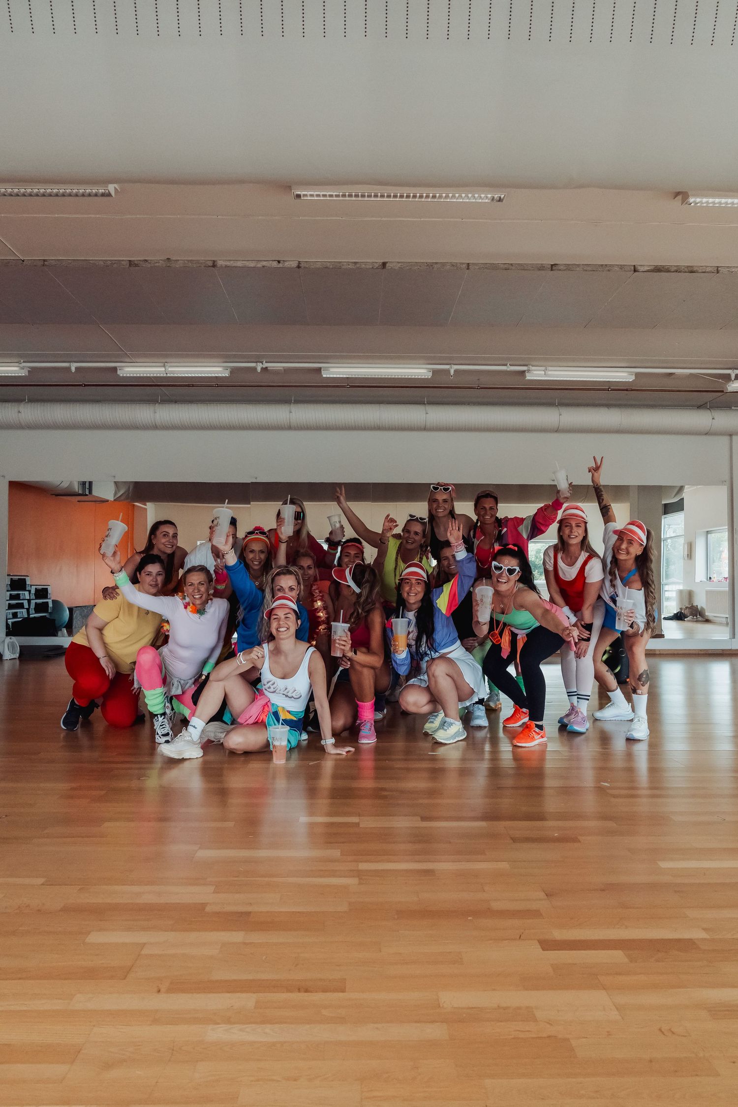 Group of dancers lying on wooden floor striking playful poses during dance class in bright studio space. bergen
