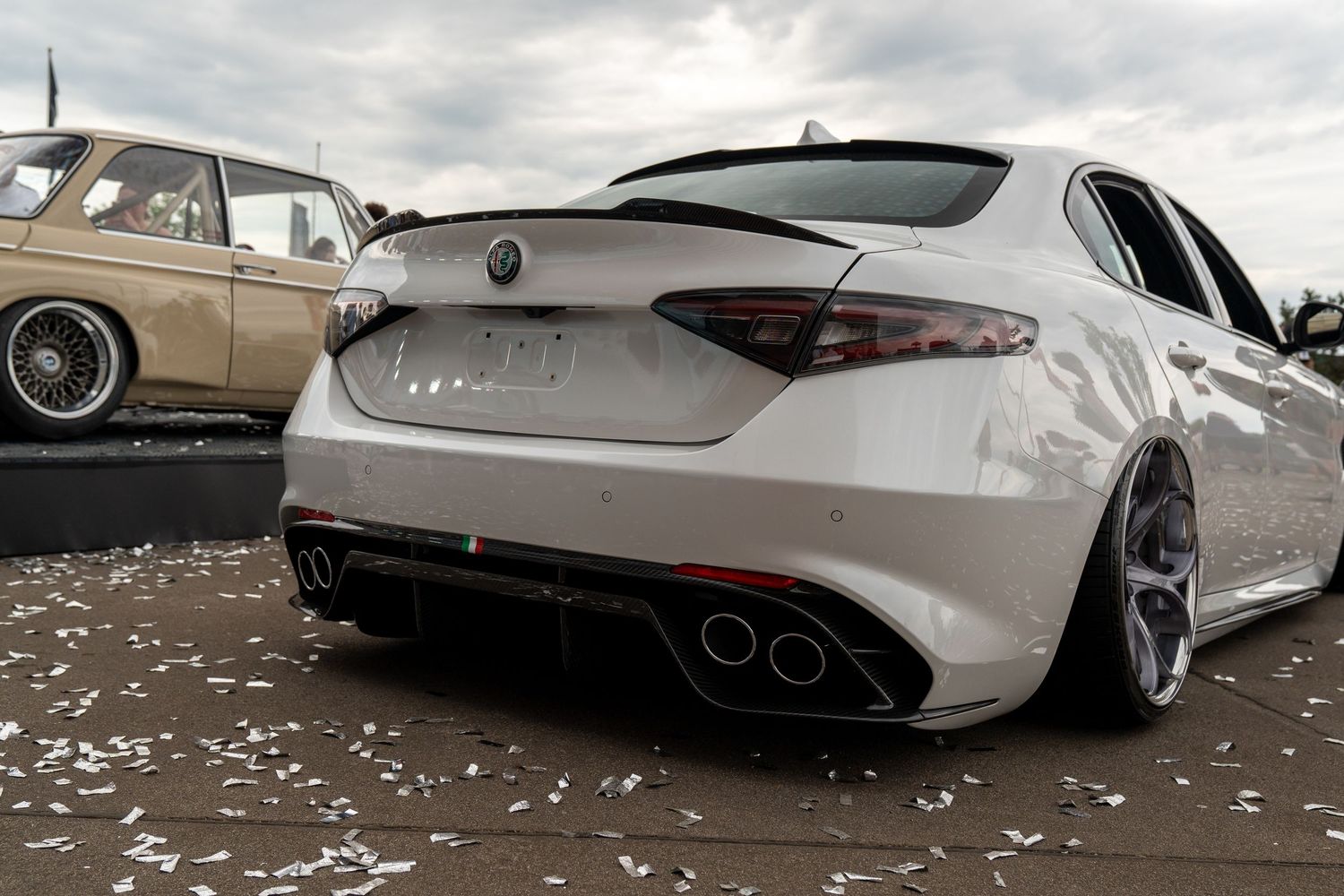 Low-angle view of modified luxury sedans with custom wheels and lowered suspension.