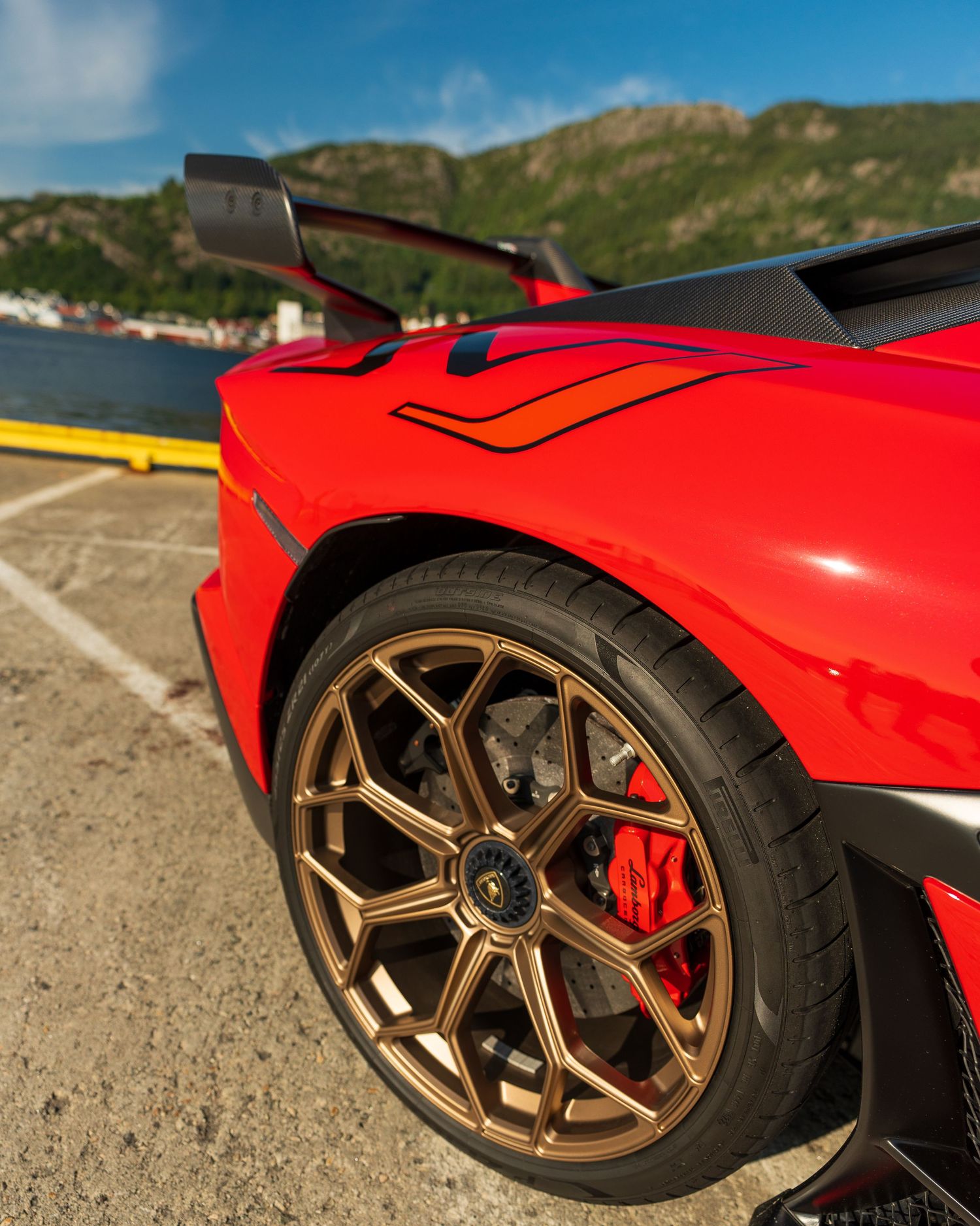 Close-up of a red sports car's wheel and fender with bronze alloy wheels and large brake calipers.
