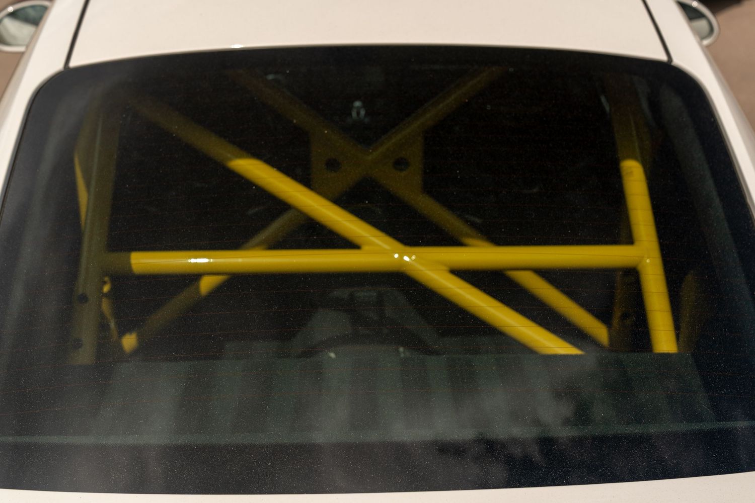 Yellow roll cage visible through rear window of a sports car.