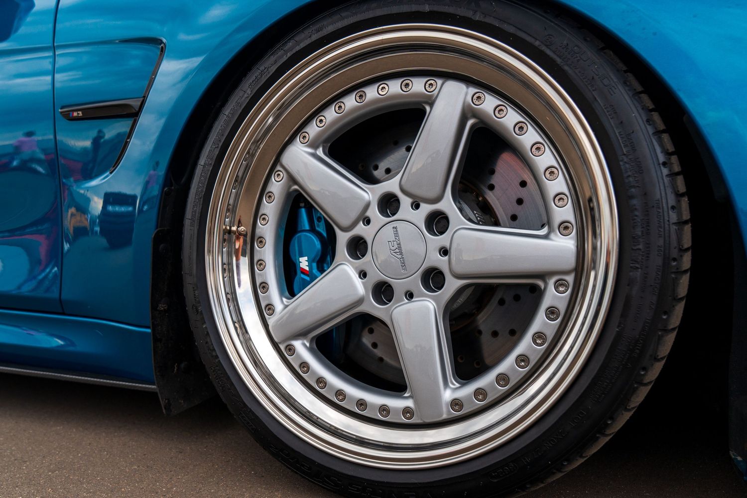 Close-up of a polished five-spoke wheel with chrome lip and performance brake caliper visible.