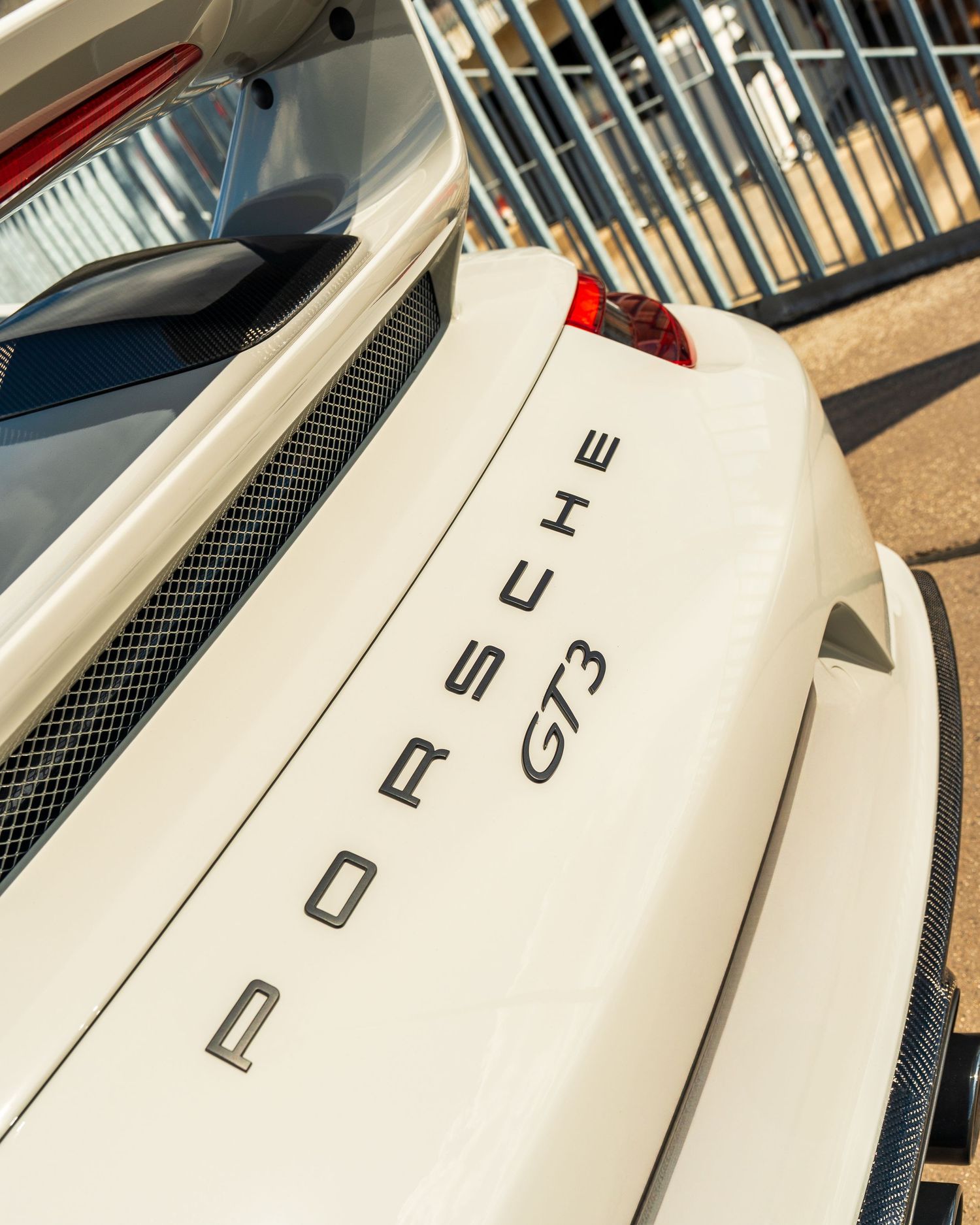 Close-up detail shot of a white Porsche GT3 rear badging against a blurred background.