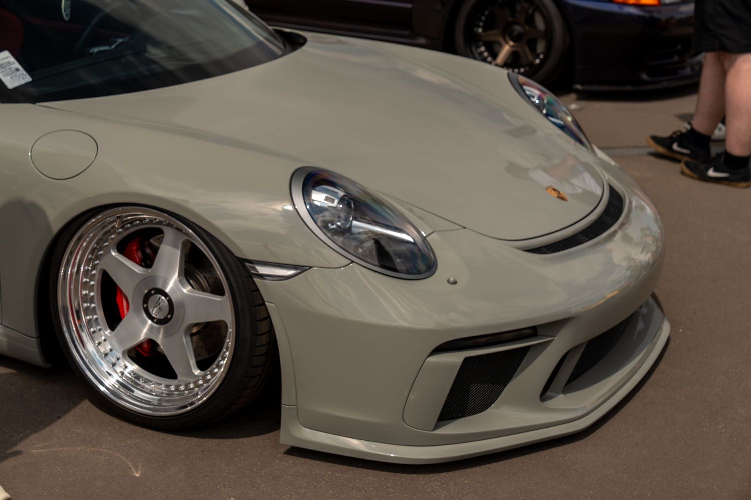Close-up view of a beige Porsche GT3 front end with custom silver wheels and performance modifications.