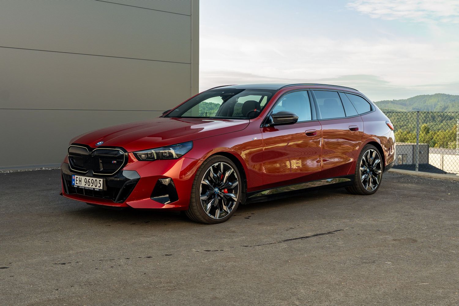 BMW M850i Gran Coupe in metallic burgundy red showcases its sleek profile against a mountain backdrop.