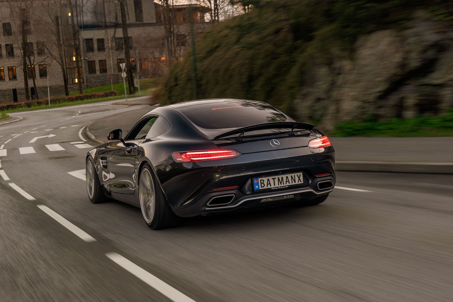 Black Mercedes-AMG GT cruising through curved city street with dynamic motion blur.