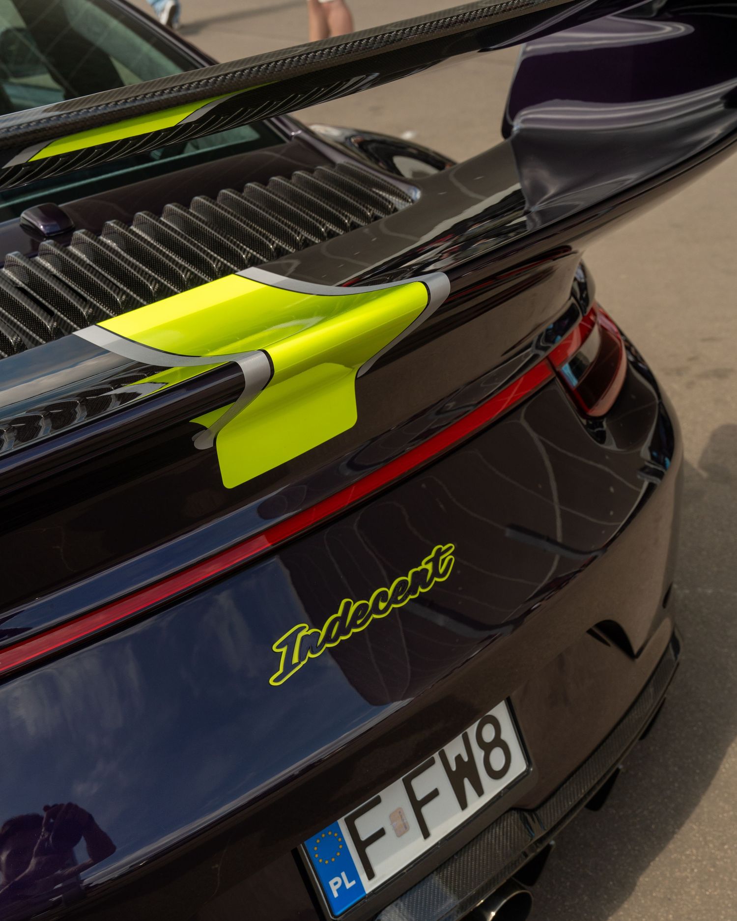 Close-up of a black Porsche rear spoiler with neon yellow accents.