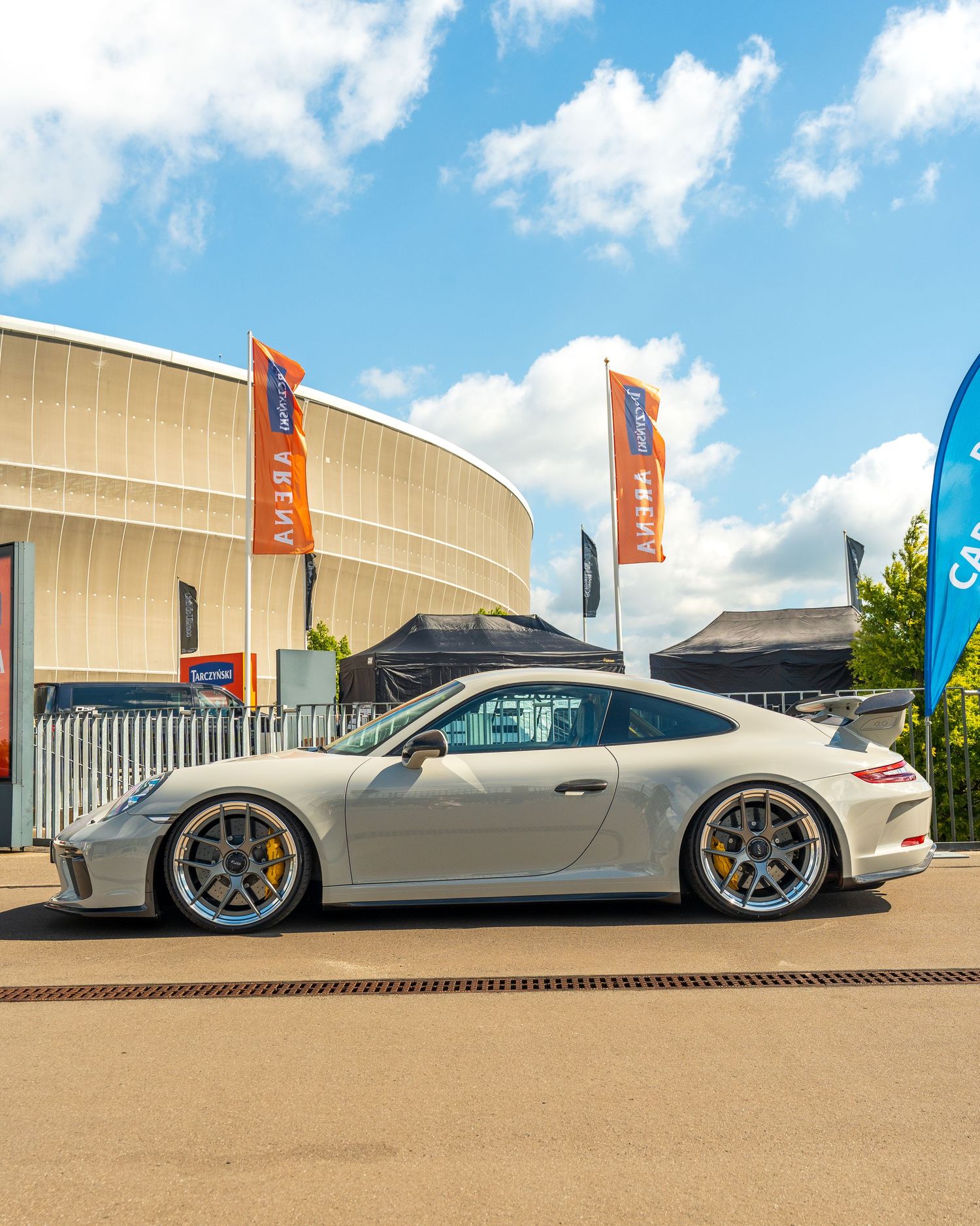 Modified silver Porsche 911 GT3 with wide body kit and custom wheels displayed at an outdoor event.