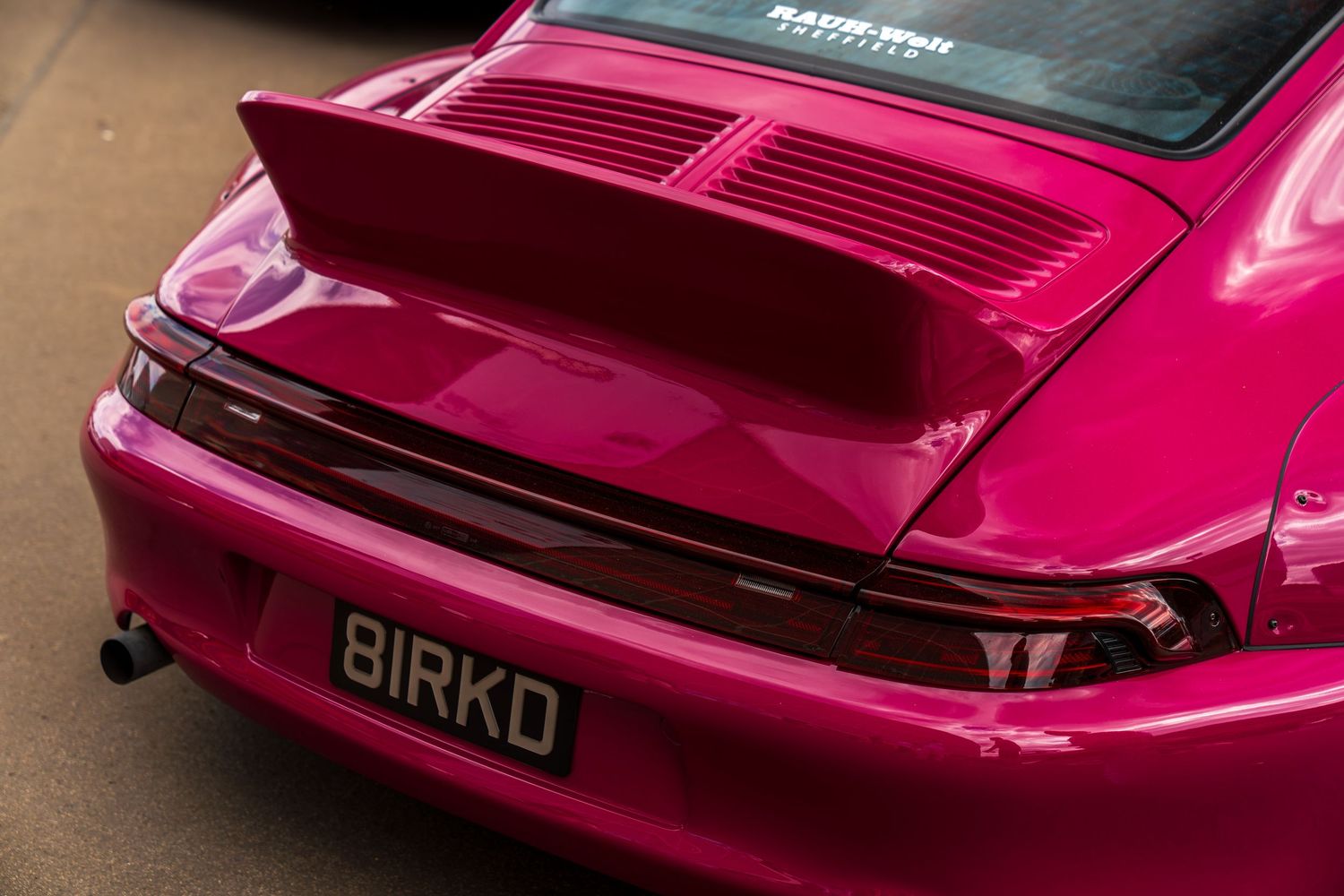 Hot pink modified sports car rear detail showing custom bodywork and spoiler.