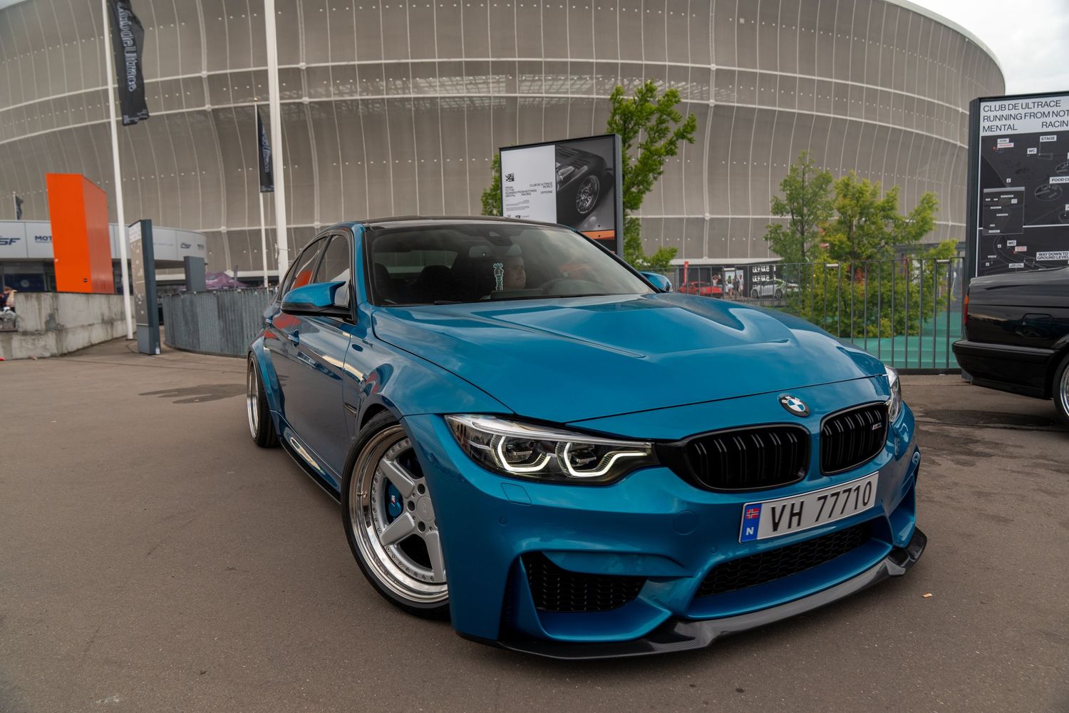 Modified BMW M4 in bright blue with aggressive stance and custom wheels.