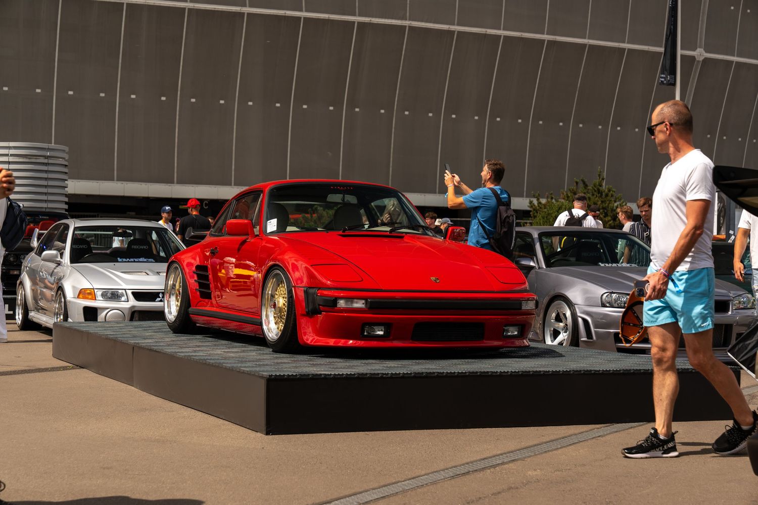 Classic red Porsche 911 on display platform at automotive event.