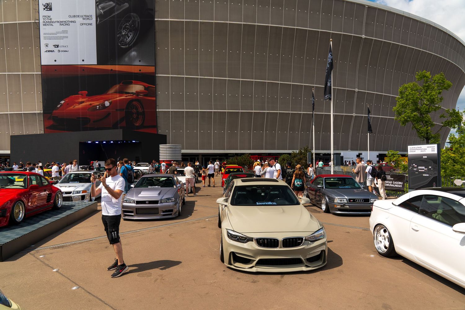 Panoramic view of luxury sports cars displayed at outdoor automotive event.