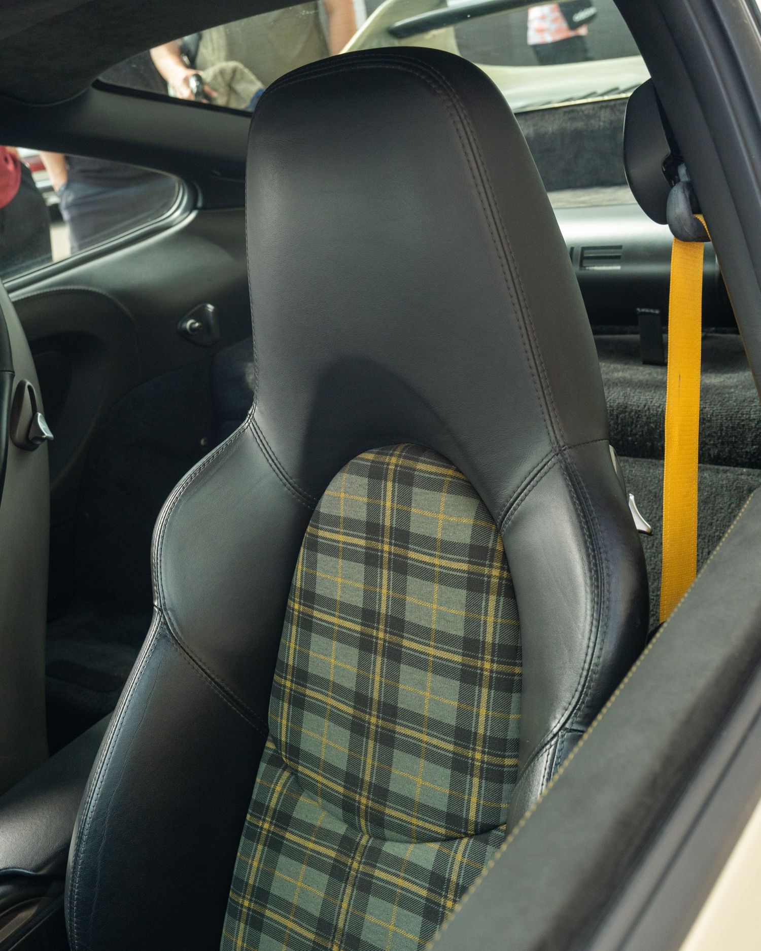 Sports car seat with black leather and plaid fabric insert cushioning showing luxury interior detail.