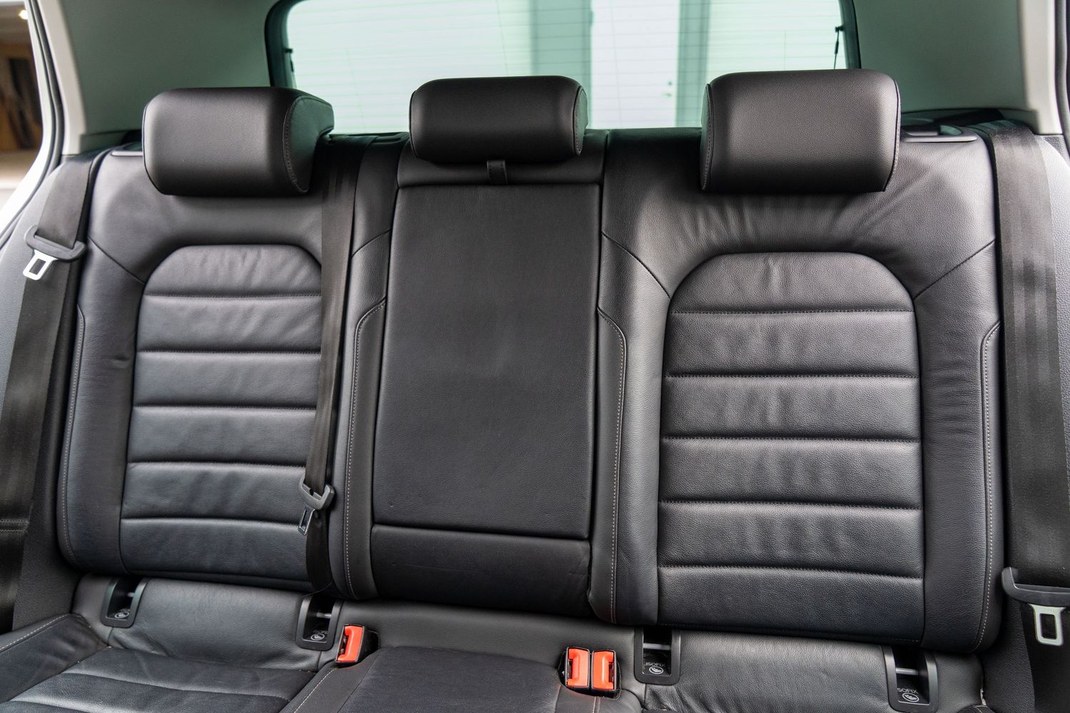 Luxurious black leather rear car seats with center armrest and headrests in a premium vehicle interior.