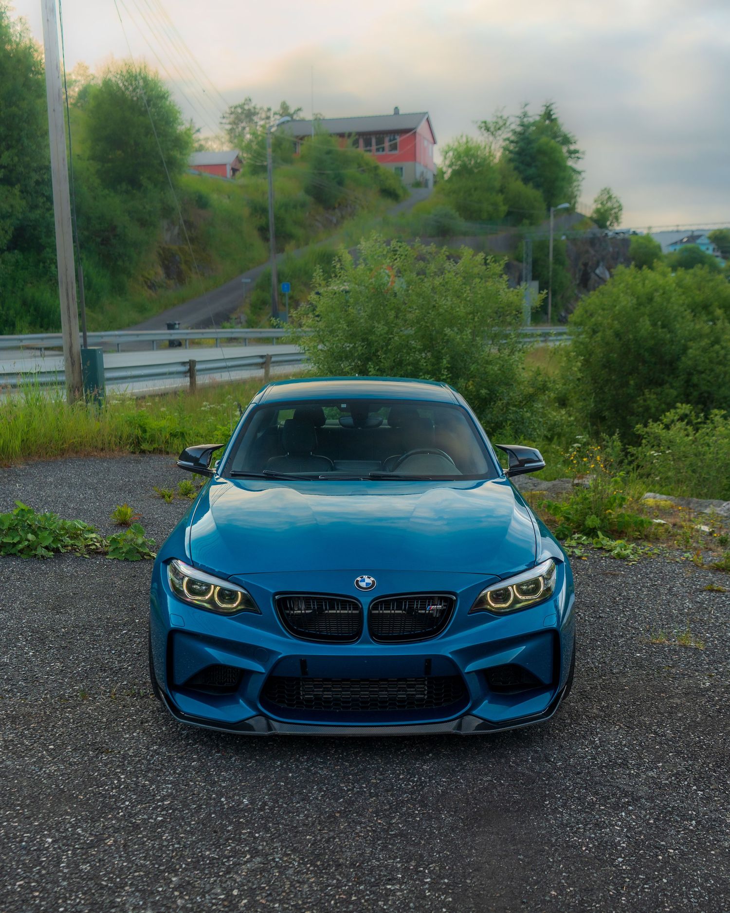 BMW M2 in Long Beach Blue metallic showcasing its aggressive front end design on a gravel parking area.
