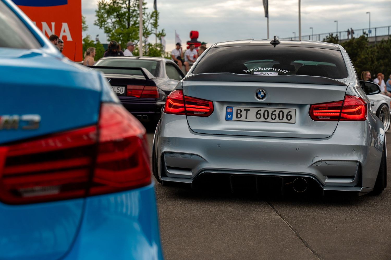 Grey BMW M3 rear view showing distinctive LED taillights and license plate in a parking lot.