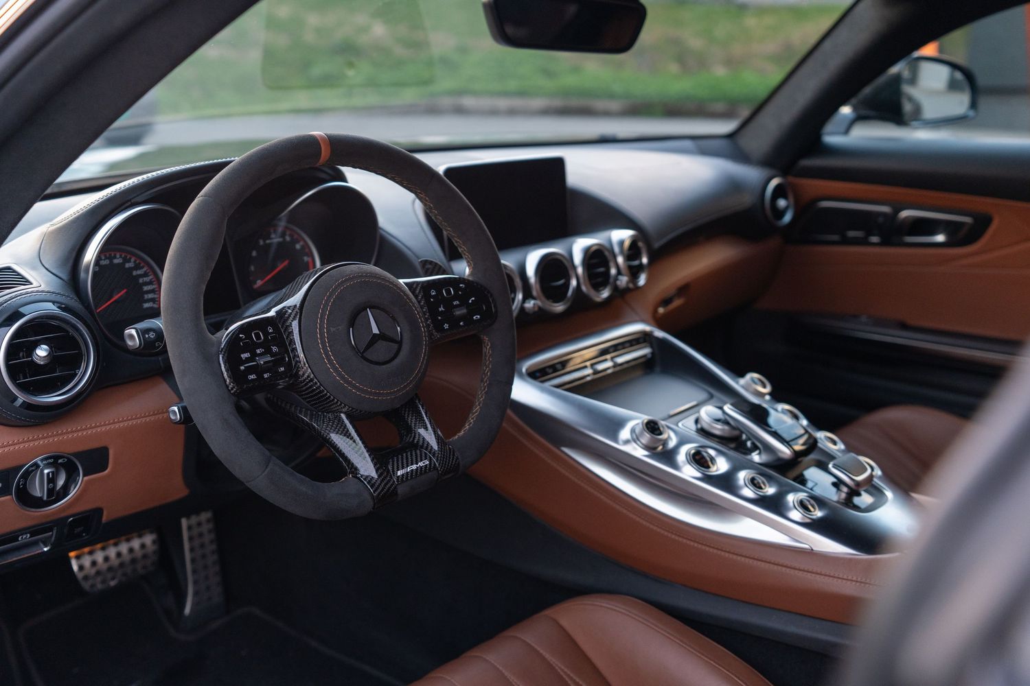 Luxury cockpit of Mercedes-AMG GT with brown leather interior and modern center console.