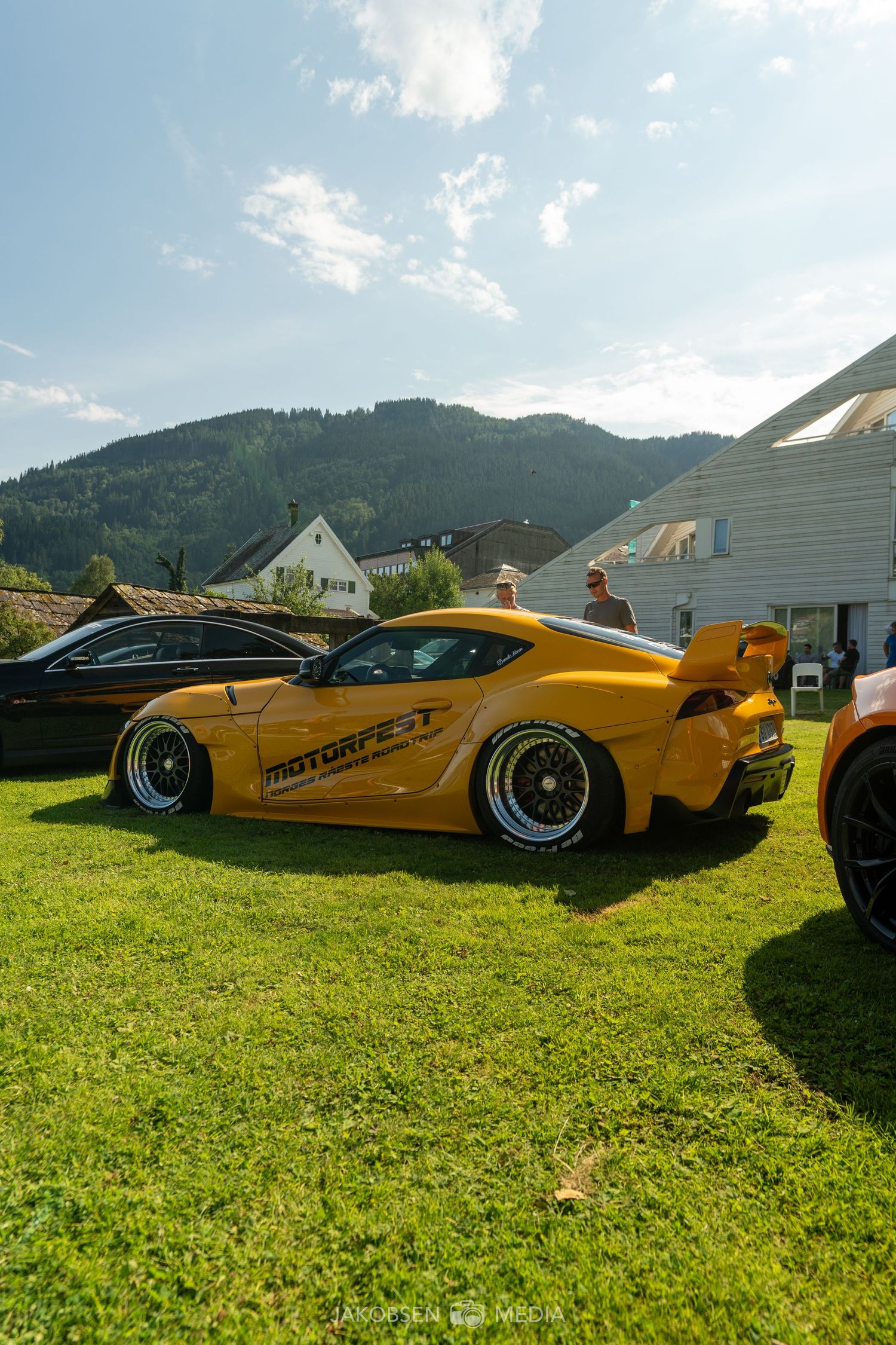 Custom yellow sports car with racing modifications shown from multiple angles on grass.