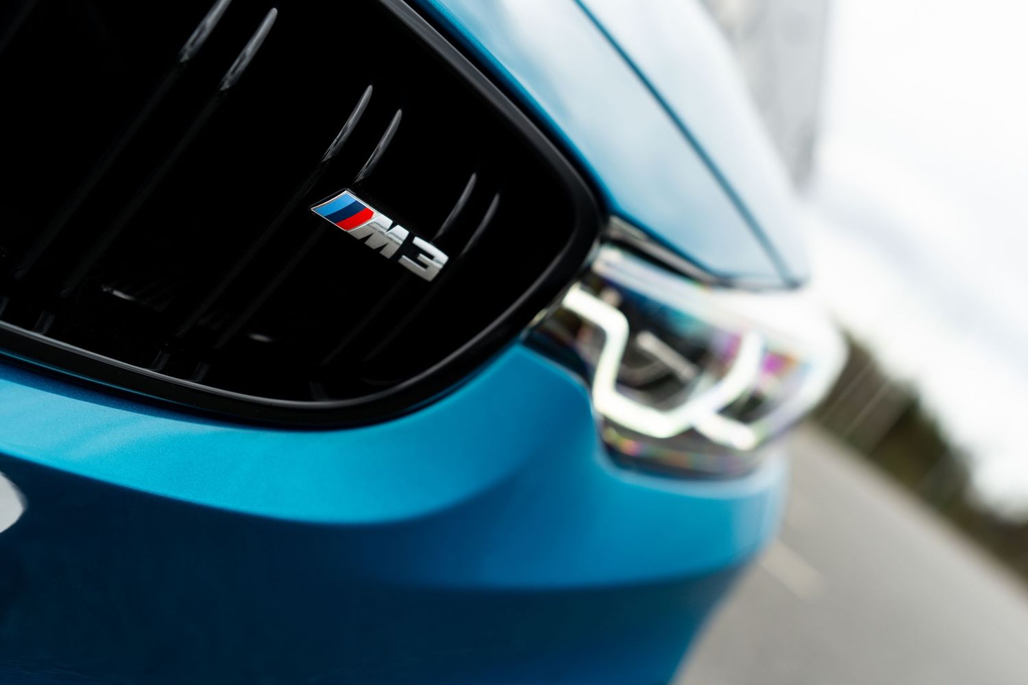 Close-up details of a blue BMW M2 sports car exterior showing badging and body panels.
