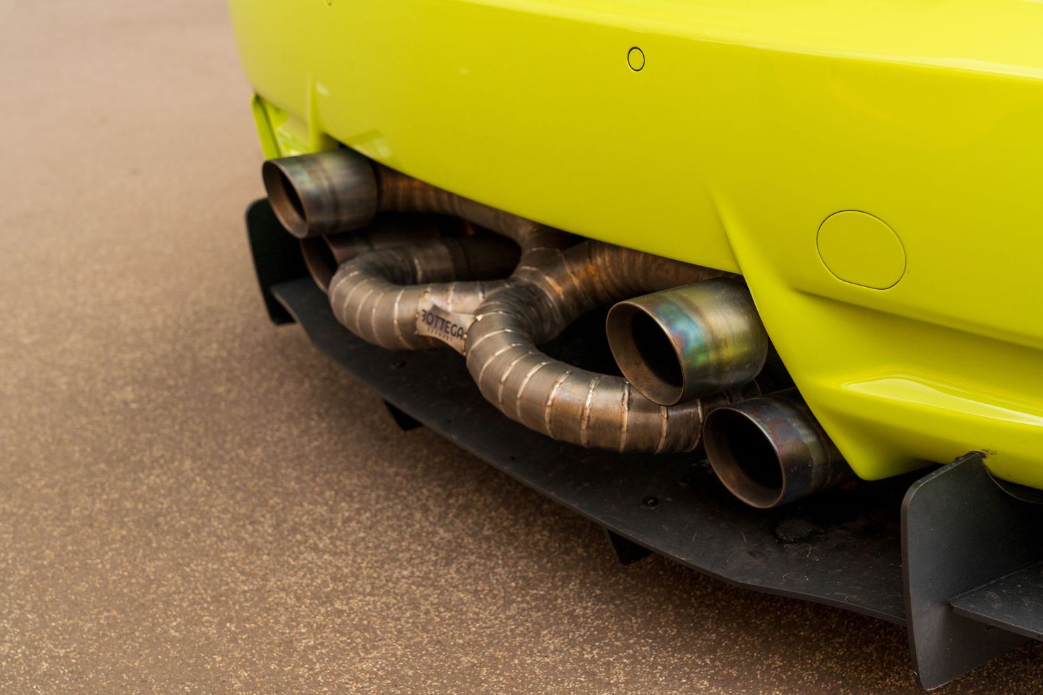 Yellow sports car with custom exhaust system and lowered suspension visible from underneath.
