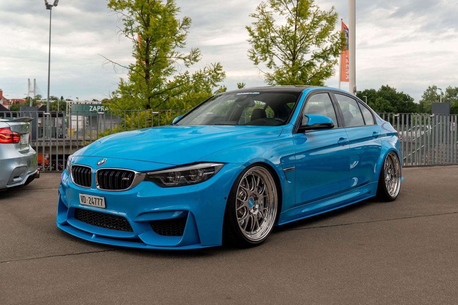 Bright blue BMW M3 with custom wheels and modified bodywork at car event.