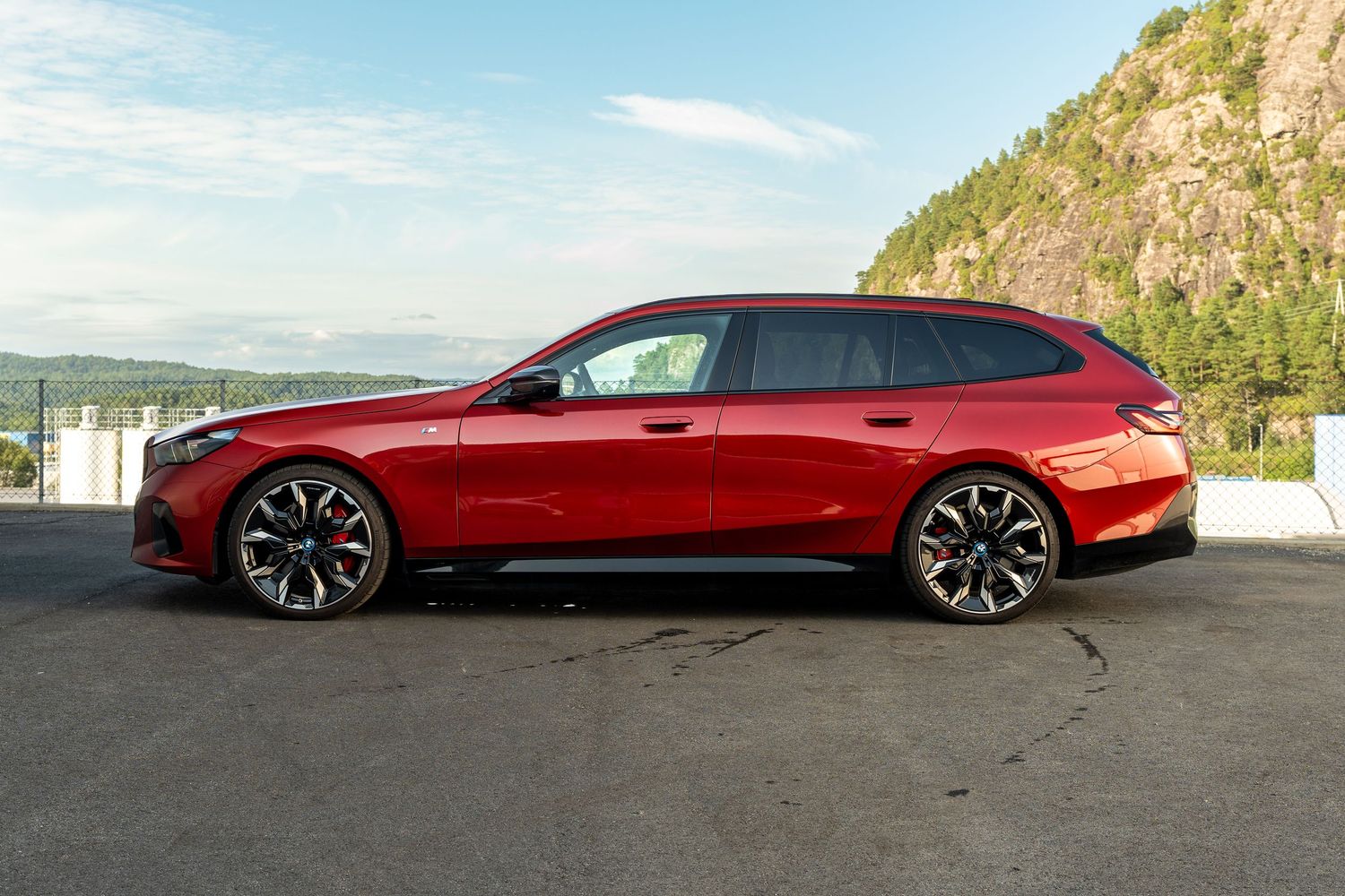 A sleek red Tesla Model S shown from multiple angles parked against scenic mountain and coastal backgrounds.