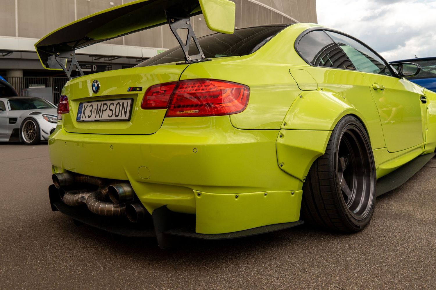 Modified BMW M3 in bright yellow showing aggressive rear diffuser and wide body kit.