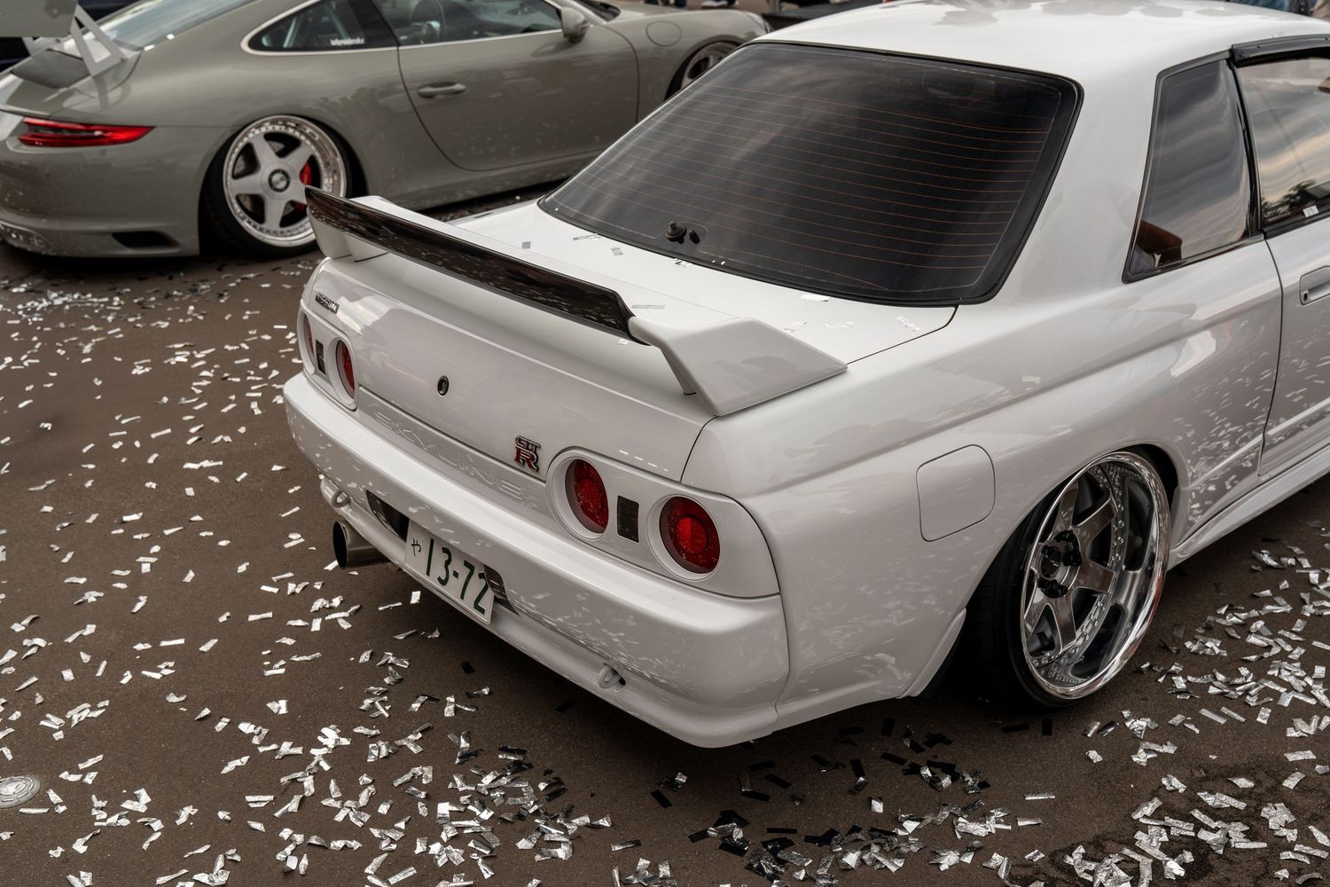 Row of white modified Nissan Skyline GT-Rs with aftermarket wheels and body modifications.