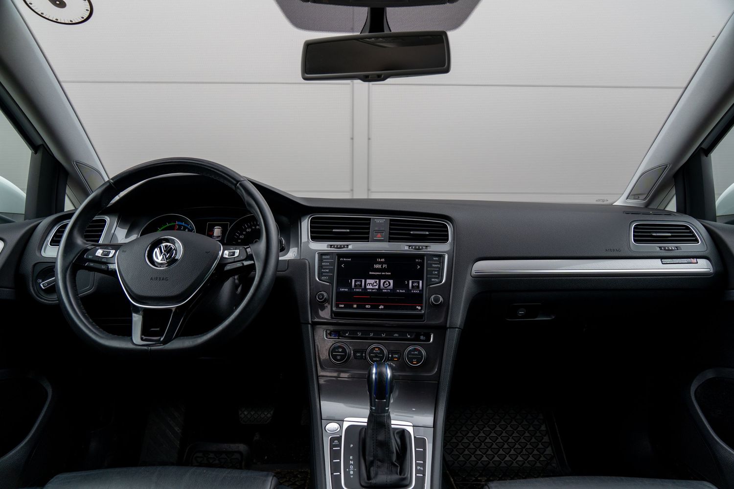 Interior view of a modern vehicle dashboard showing digital displays and leather-wrapped steering wheel.