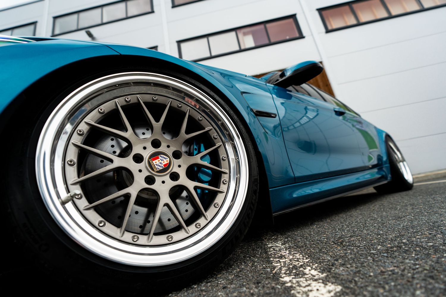 Low angle view of a modified BMW M3 with custom wheels and aggressive stance.