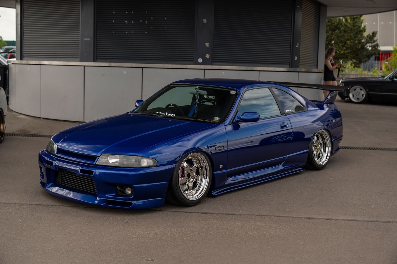 Lowered blue Nissan Silvia S15 with custom body kit and wheels.