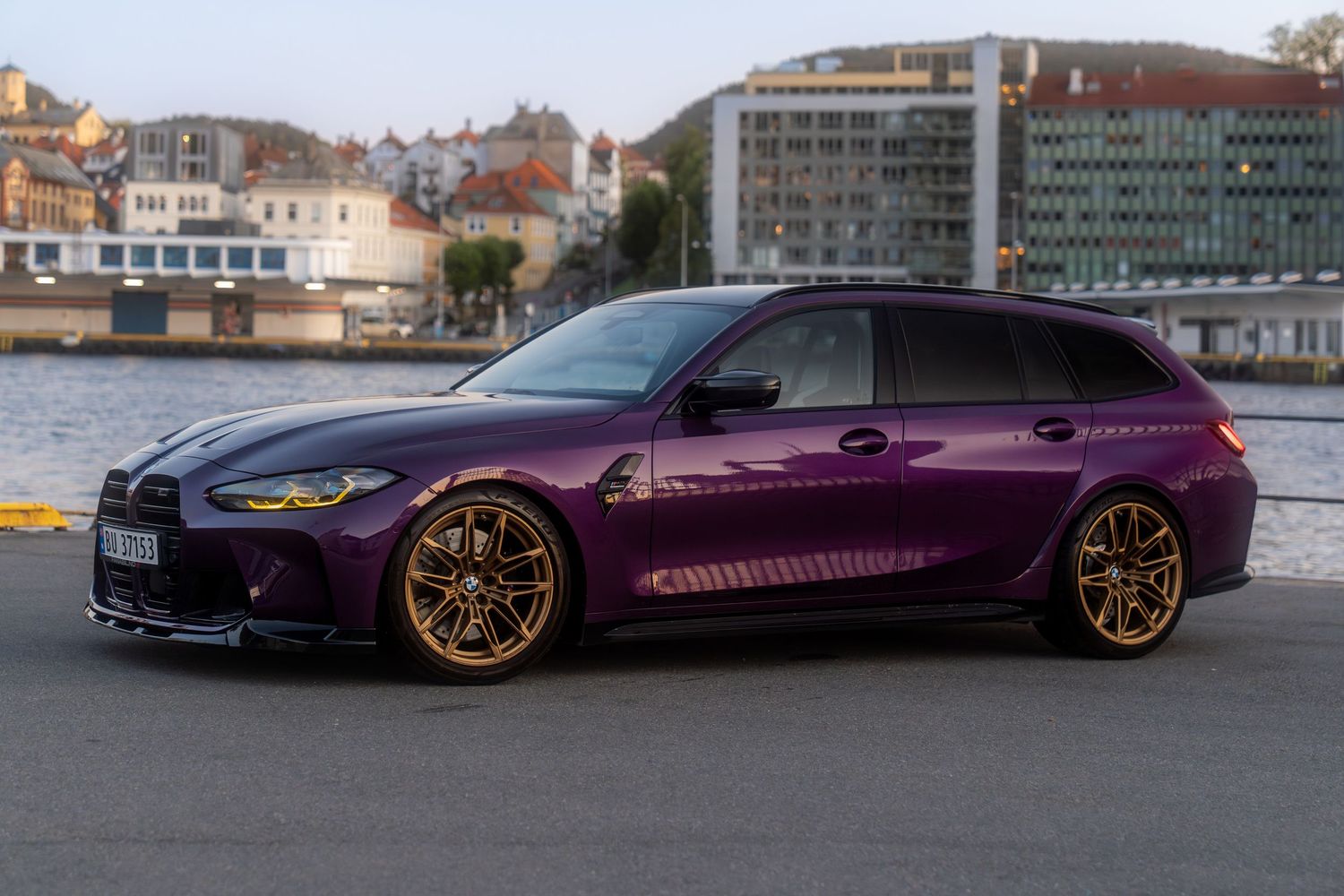 Custom lowered purple BMW M4 photographed in various poses against a waterfront cityscape background.
