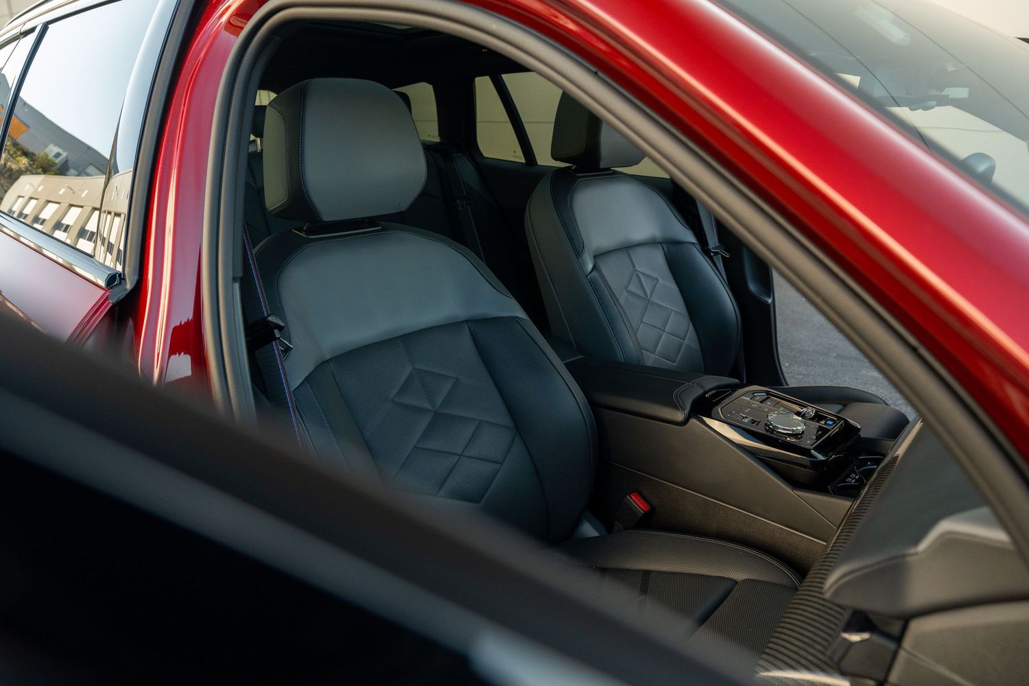 Front seats of a red luxury vehicle featuring diamond-quilted leather upholstery.