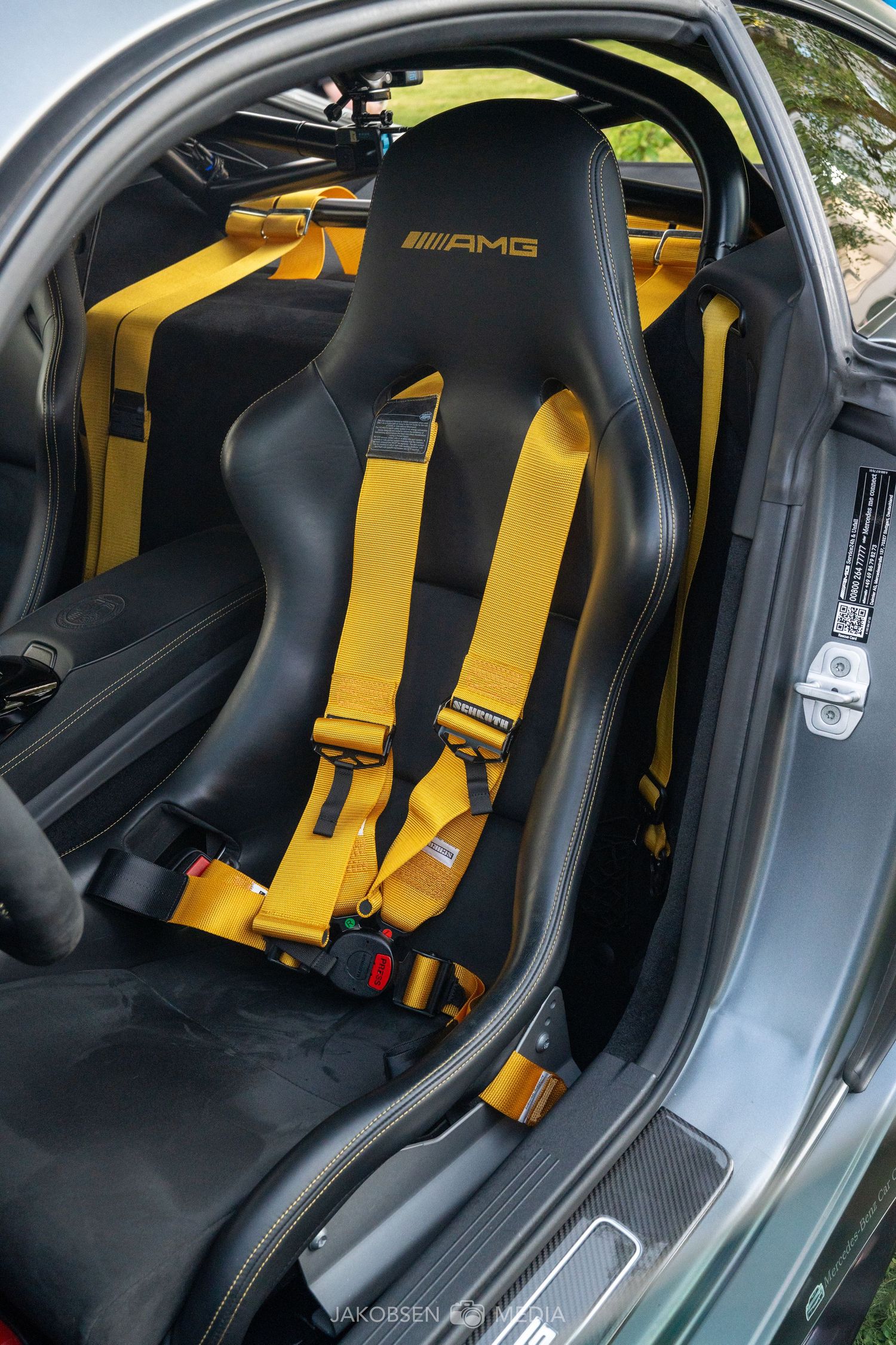 Black interior of a luxury sports car with striking yellow racing harness seatbelts.