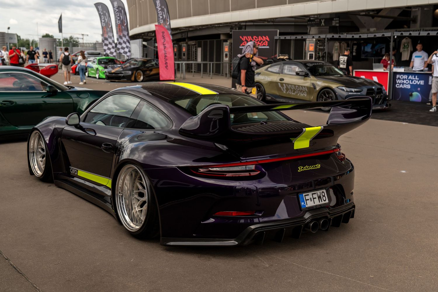 Black Porsche with aftermarket wheels and body modifications displayed at automotive event.