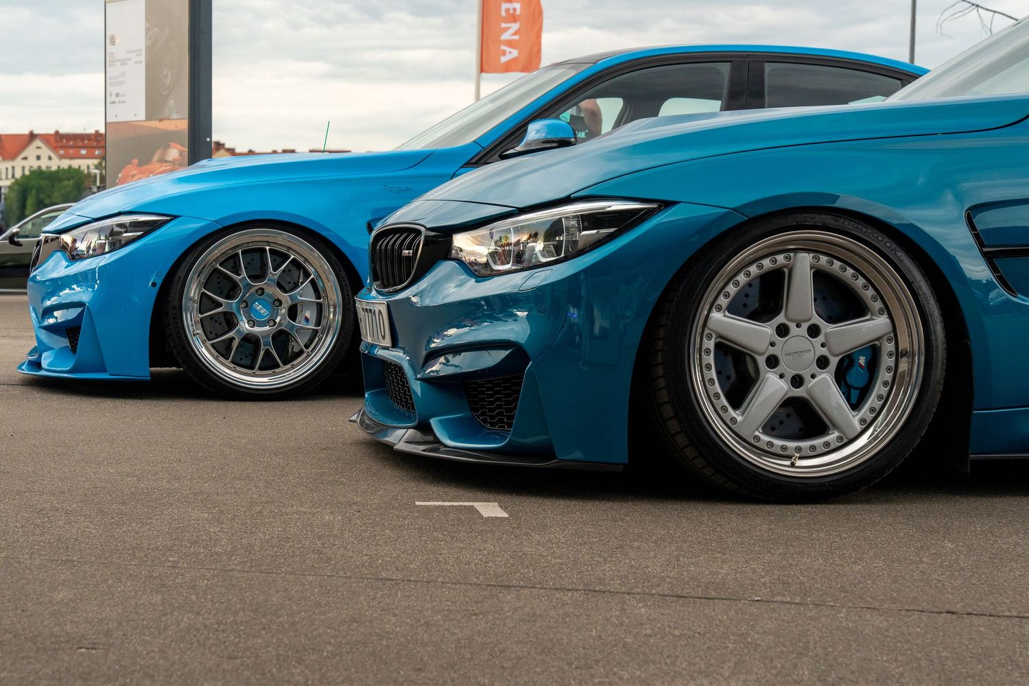 Side profile comparison of two modified BMW M3s in bright blue with custom wheels.
