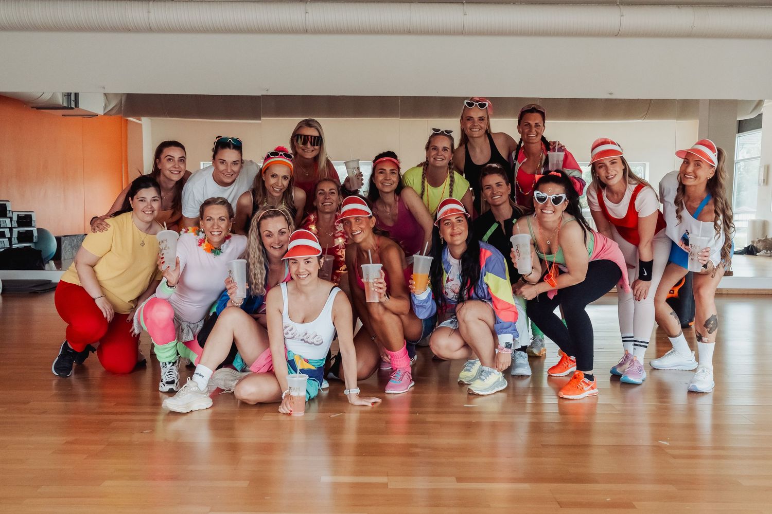 A large group poses in colorful athletic wear during a fitness event.