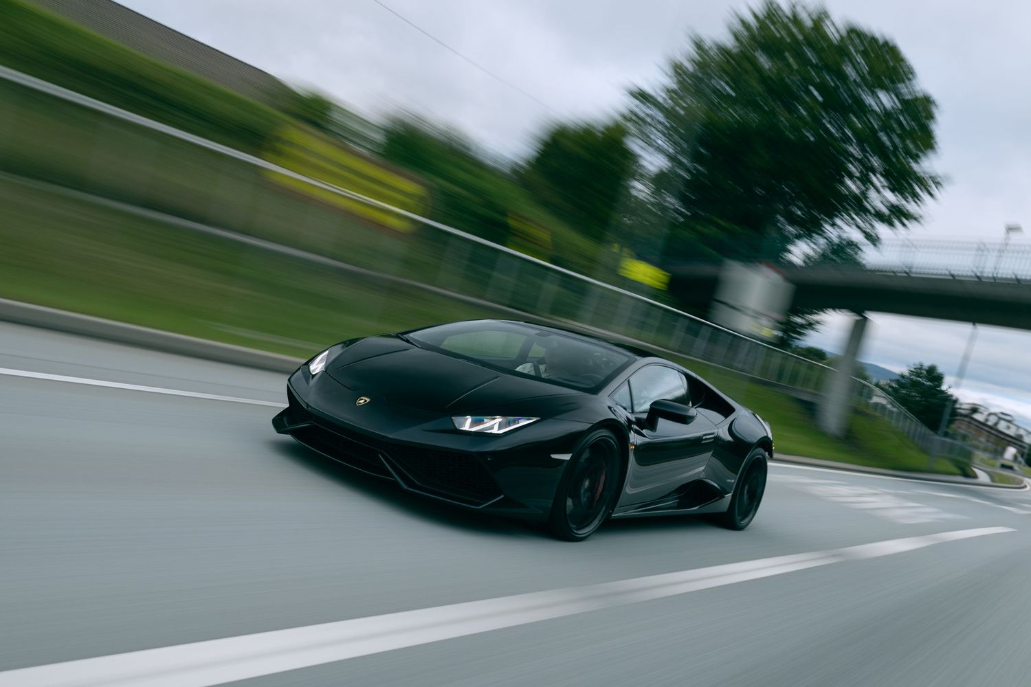 Black Lamborghini Huracan speeding on a highway with motion blur effect.
