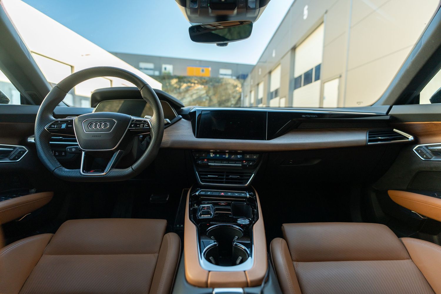 Modern Audi cockpit featuring dual screens and premium brown leather interior trim.