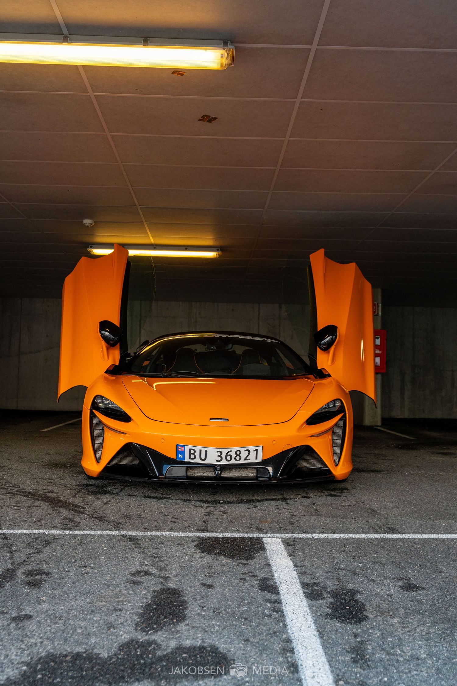 Orange McLaren supercar seen from multiple angles in a dimly lit parking garage.