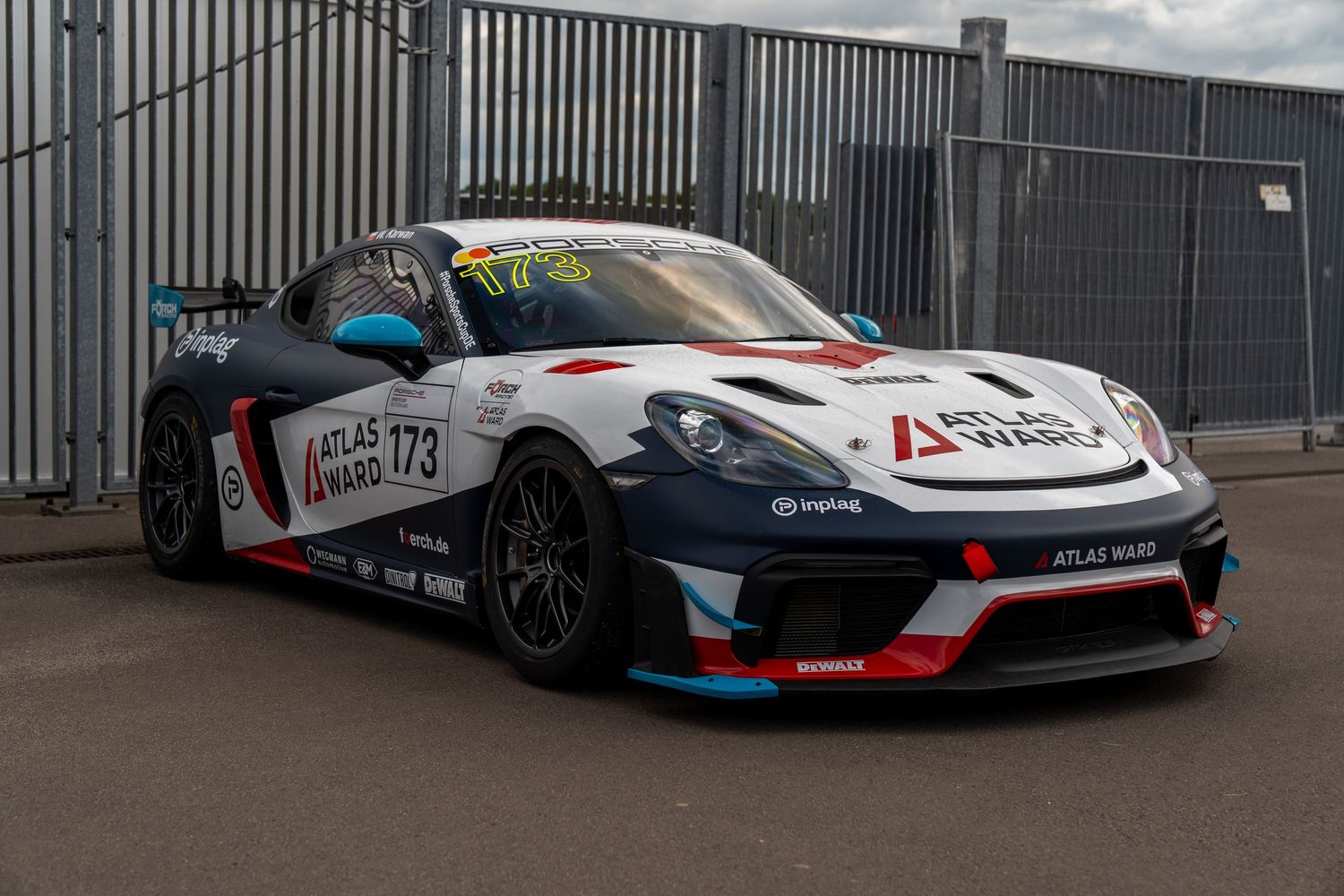 Racing cars with custom liveries and aerodynamic modifications lined up at a motorsport event.