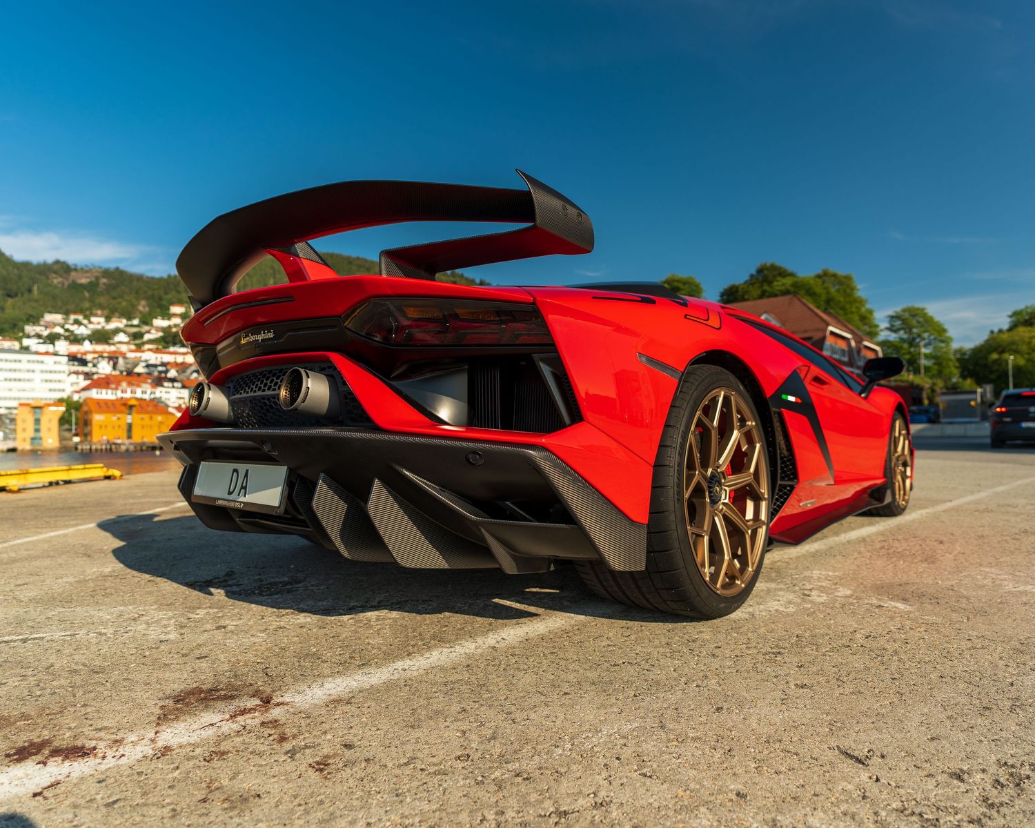 Red Lamborghini supercar captured at dramatic low angle against blue sky.