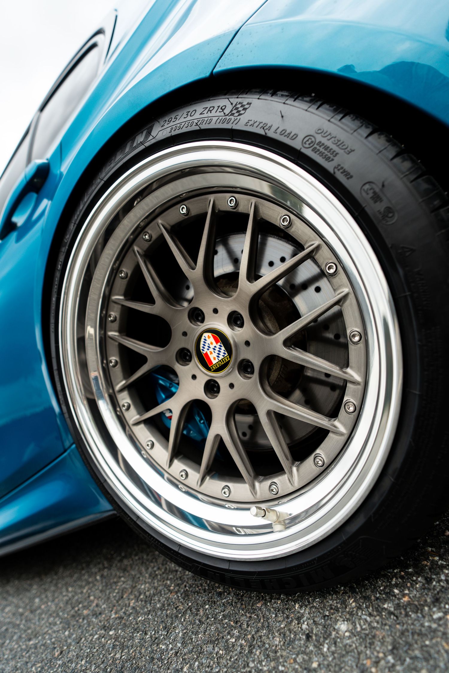 Close-up of HRE mesh wheel with polished lip and performance tire on modified BMW.
