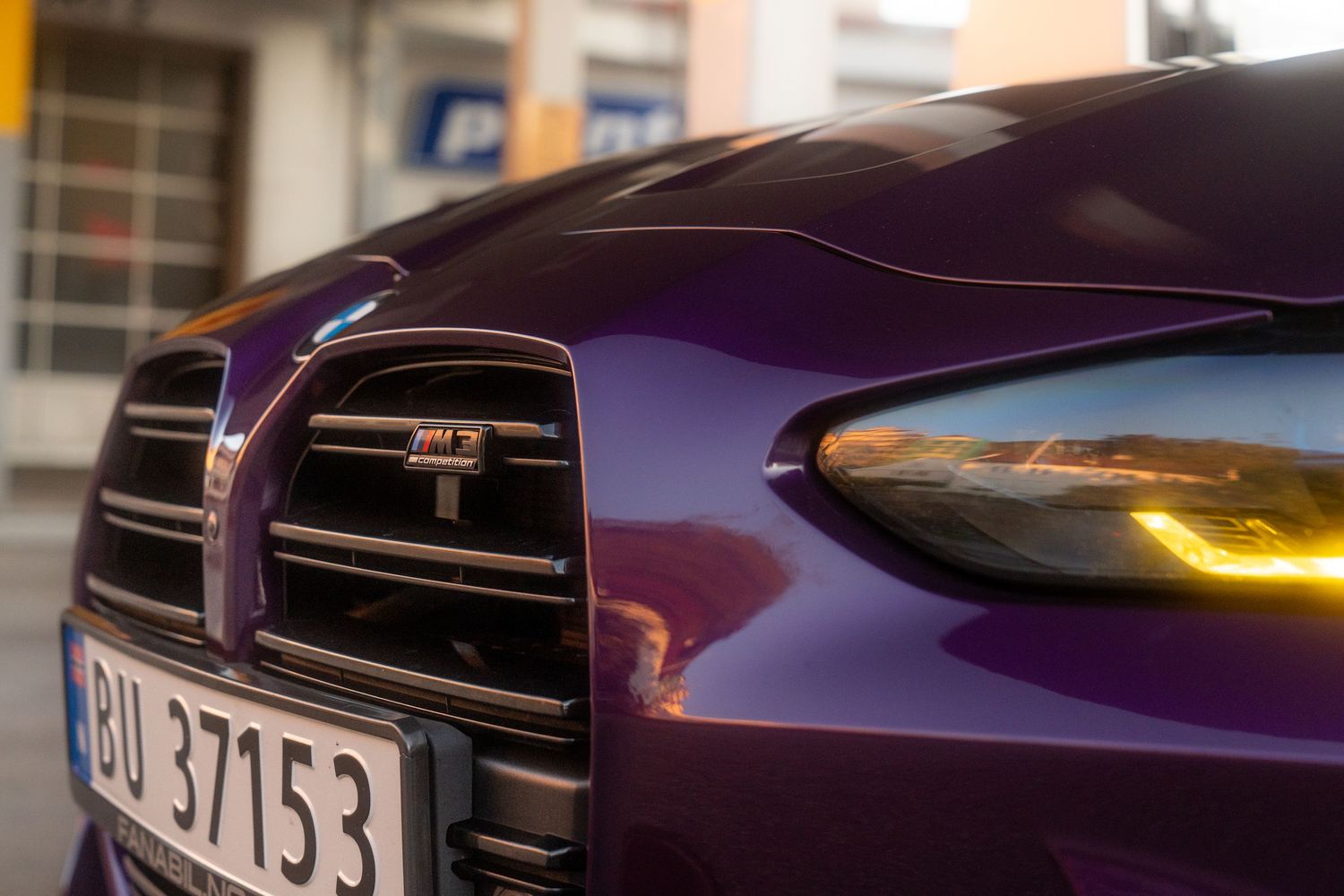 Close-up view of a purple BMW M4's aggressive front grille and headlight design.