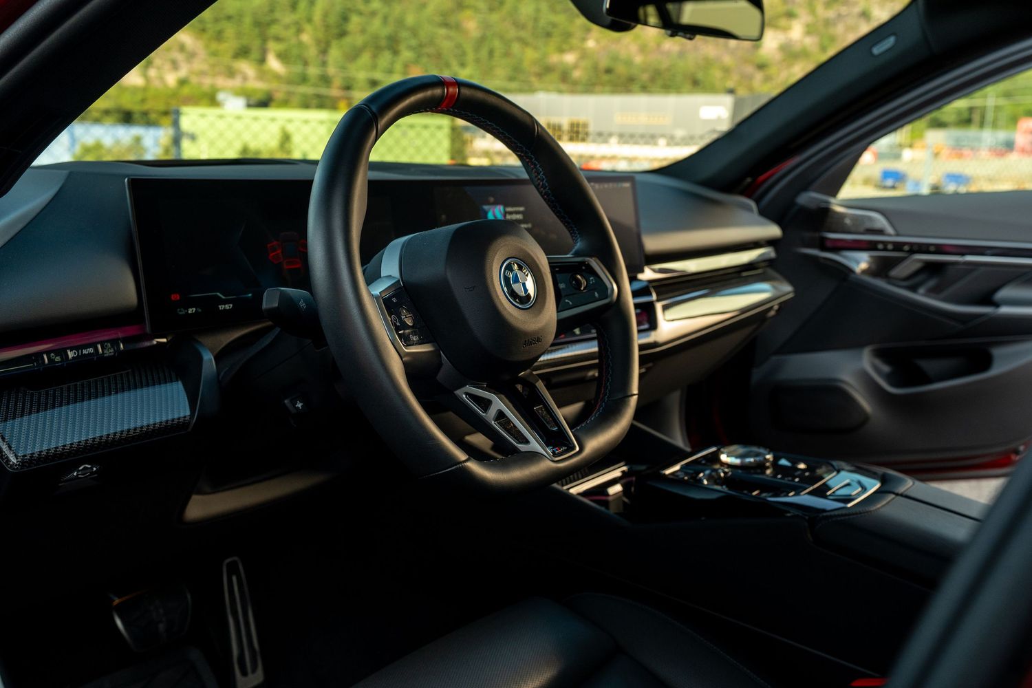 Modern BMW interior dashboard with leather steering wheel and digital displays.