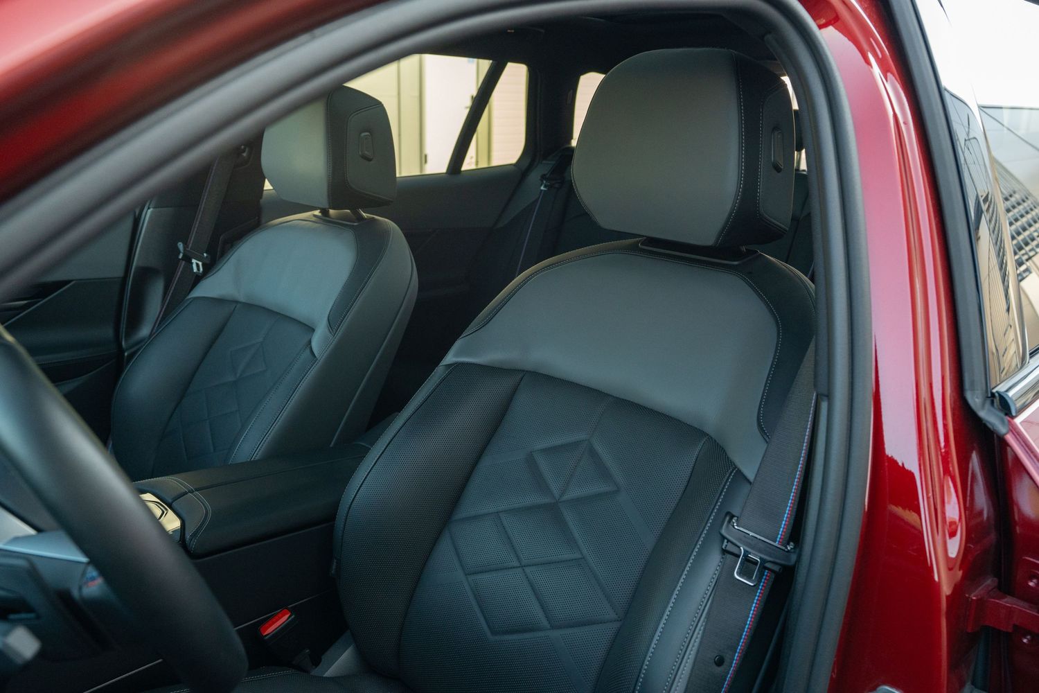 Interior view of BMW vehicle showing red leather seats and center console with digital controls.
