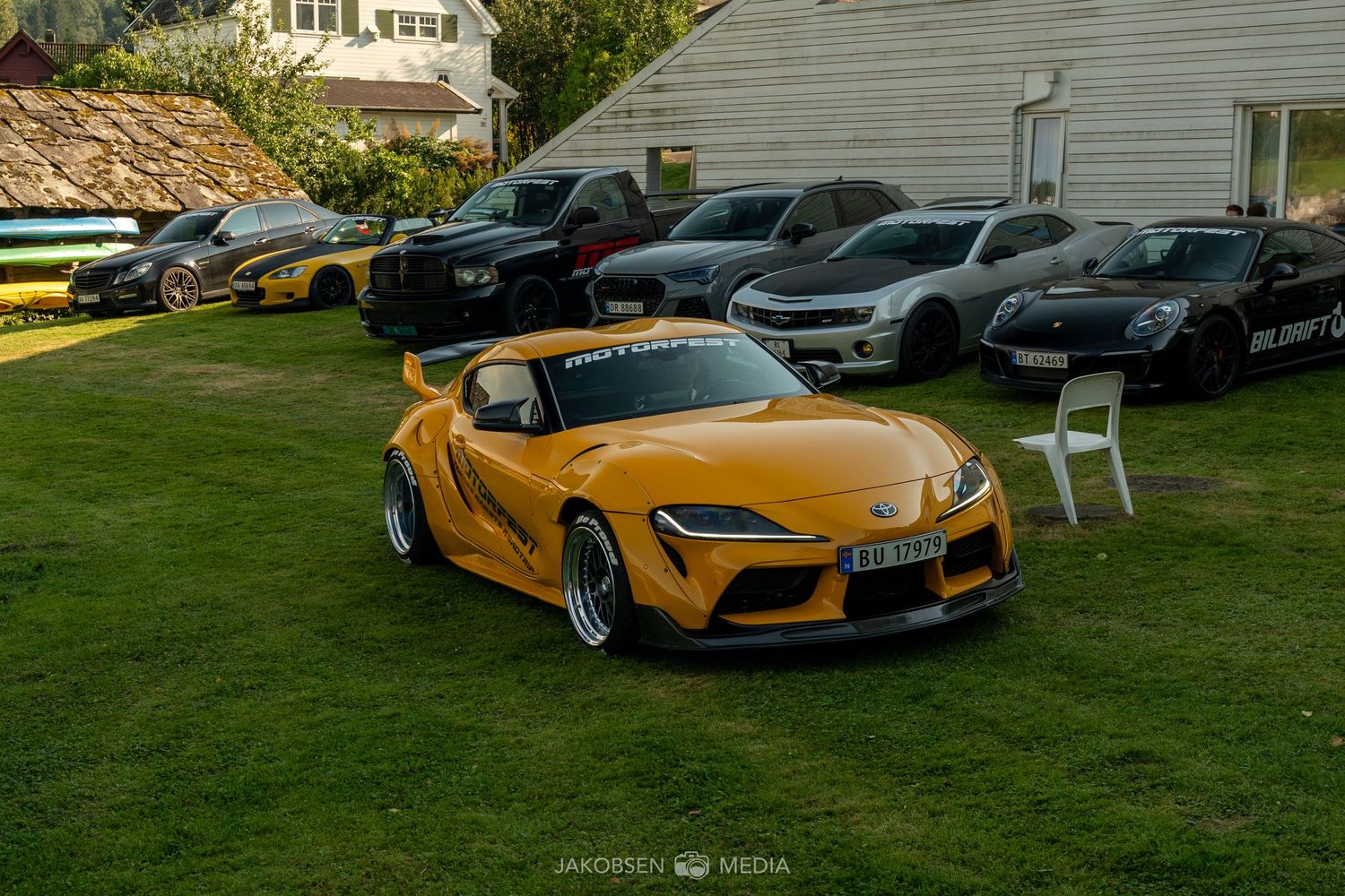 Yellow McLaren supercar alongside other luxury vehicles on display at an outdoor event.