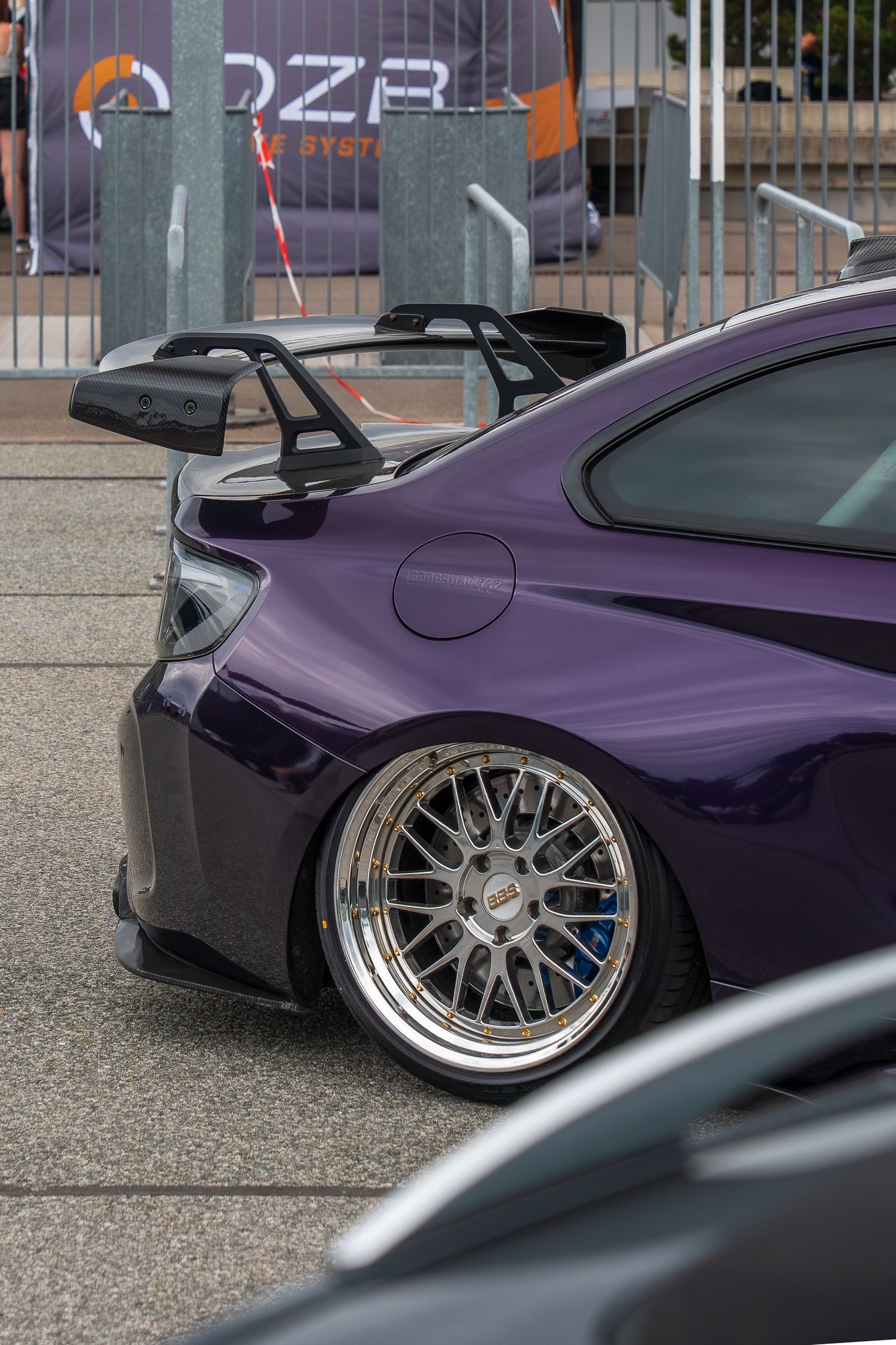 Close-up of a purple sports car with custom wide-body kit and deep-dish silver wheels.