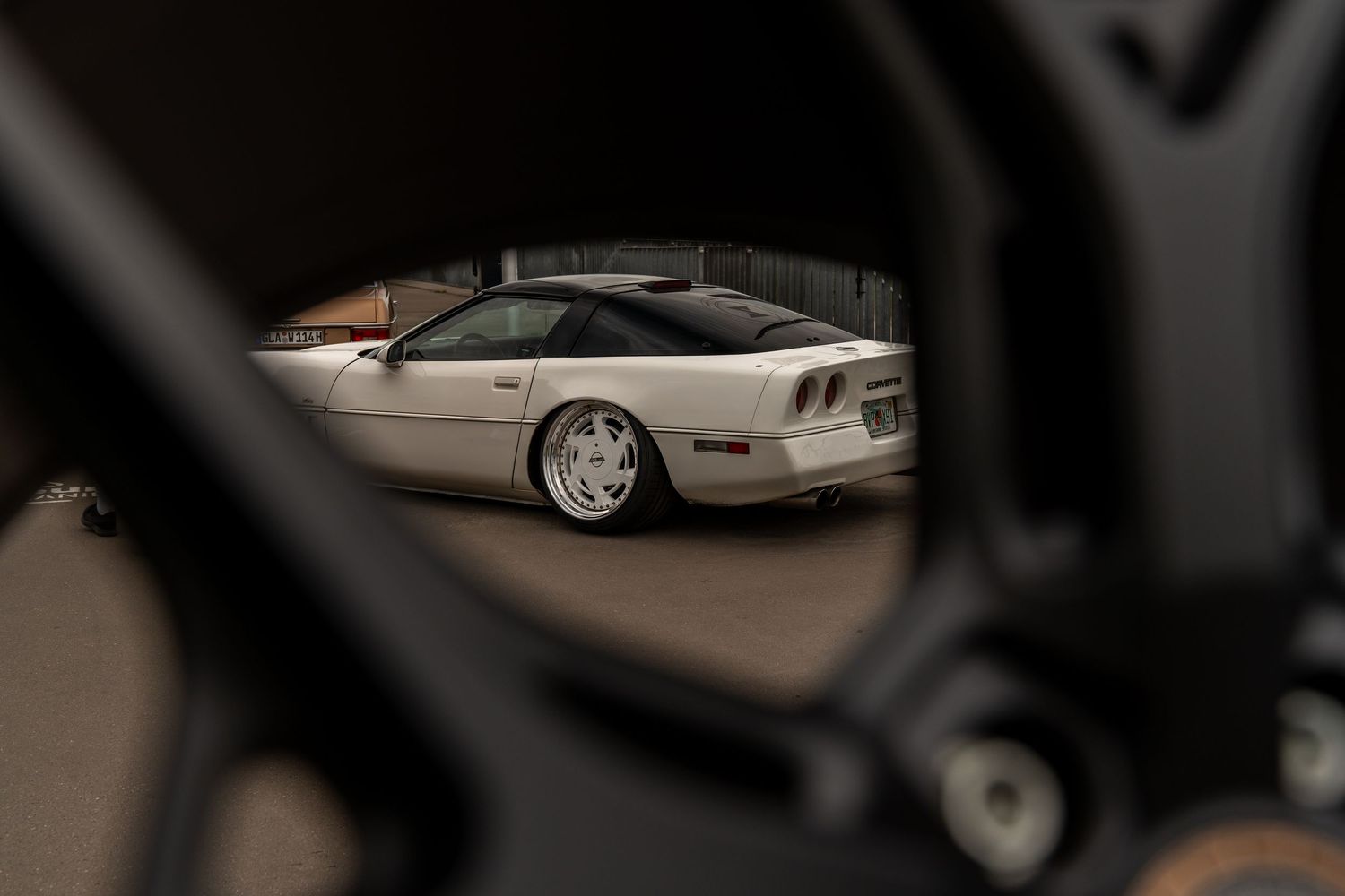Collection of modified cars parked at a car show viewed through a blurred foreground.