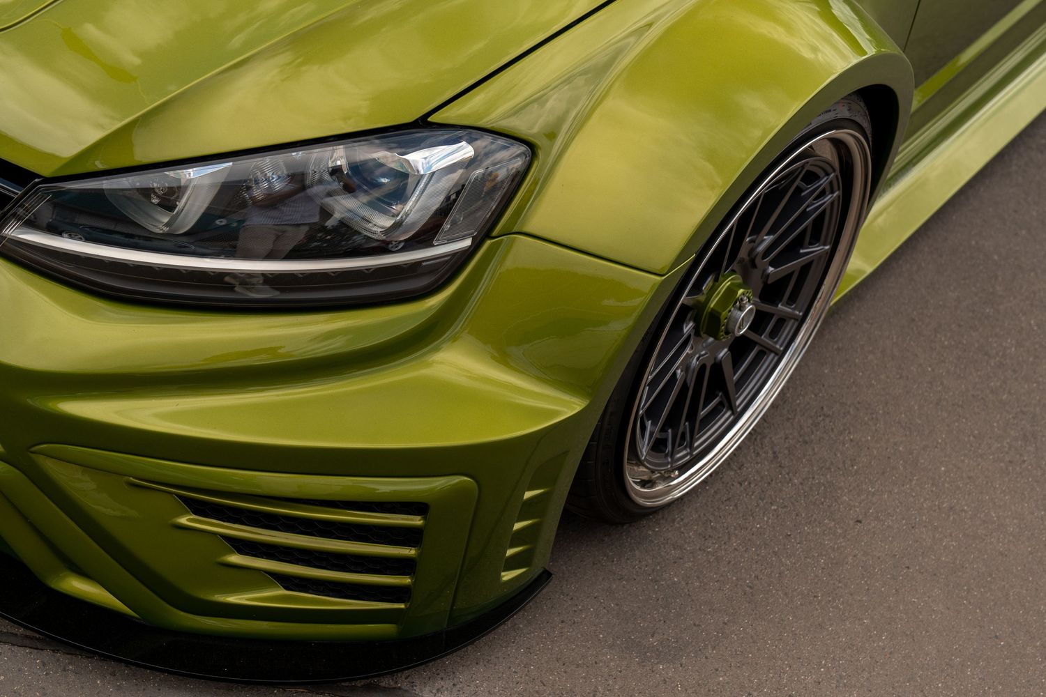 Lime green modified sports car displaying custom wheels and aerodynamic body kit.